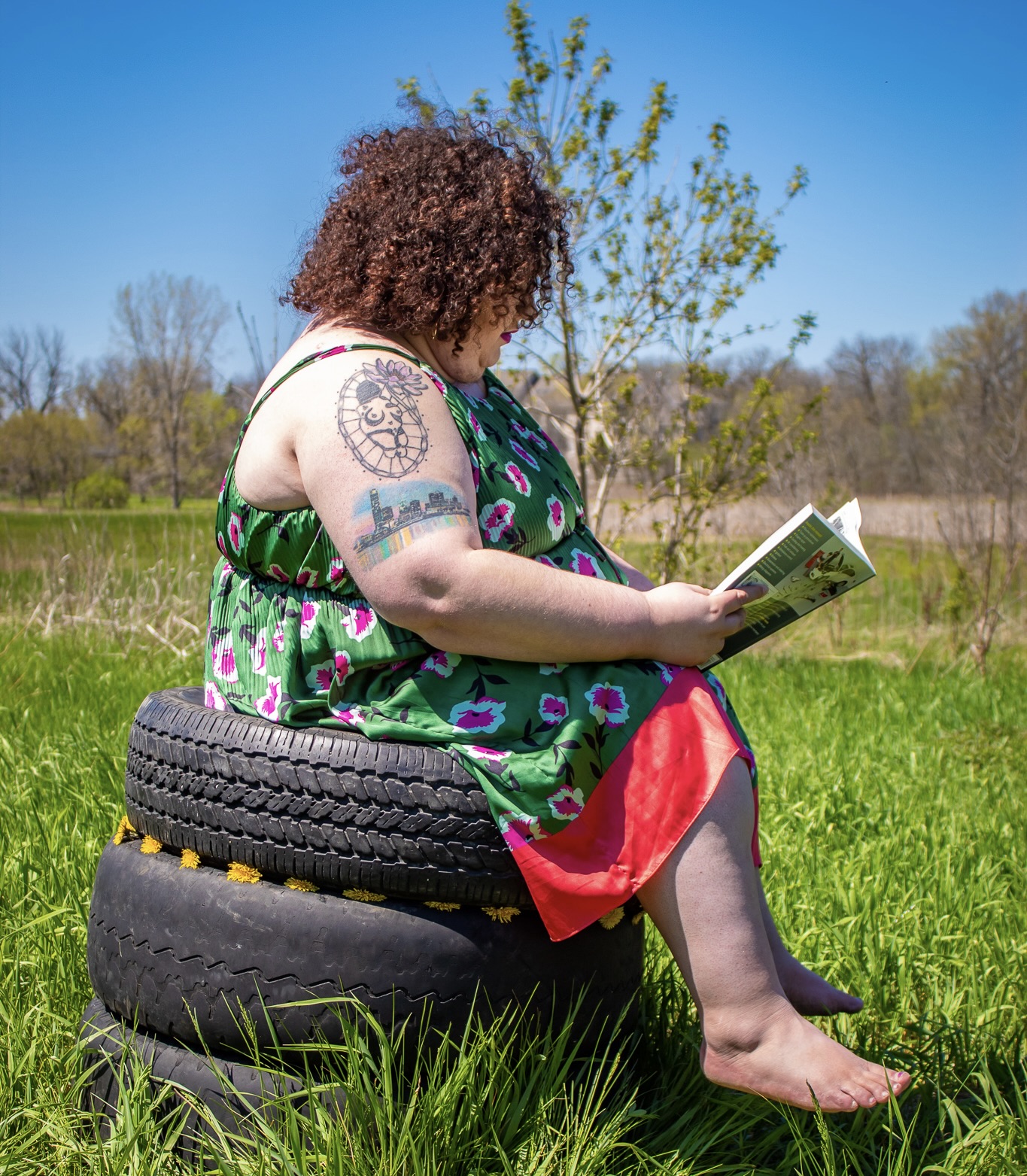Woman sitting on two tires readying about car maintenance