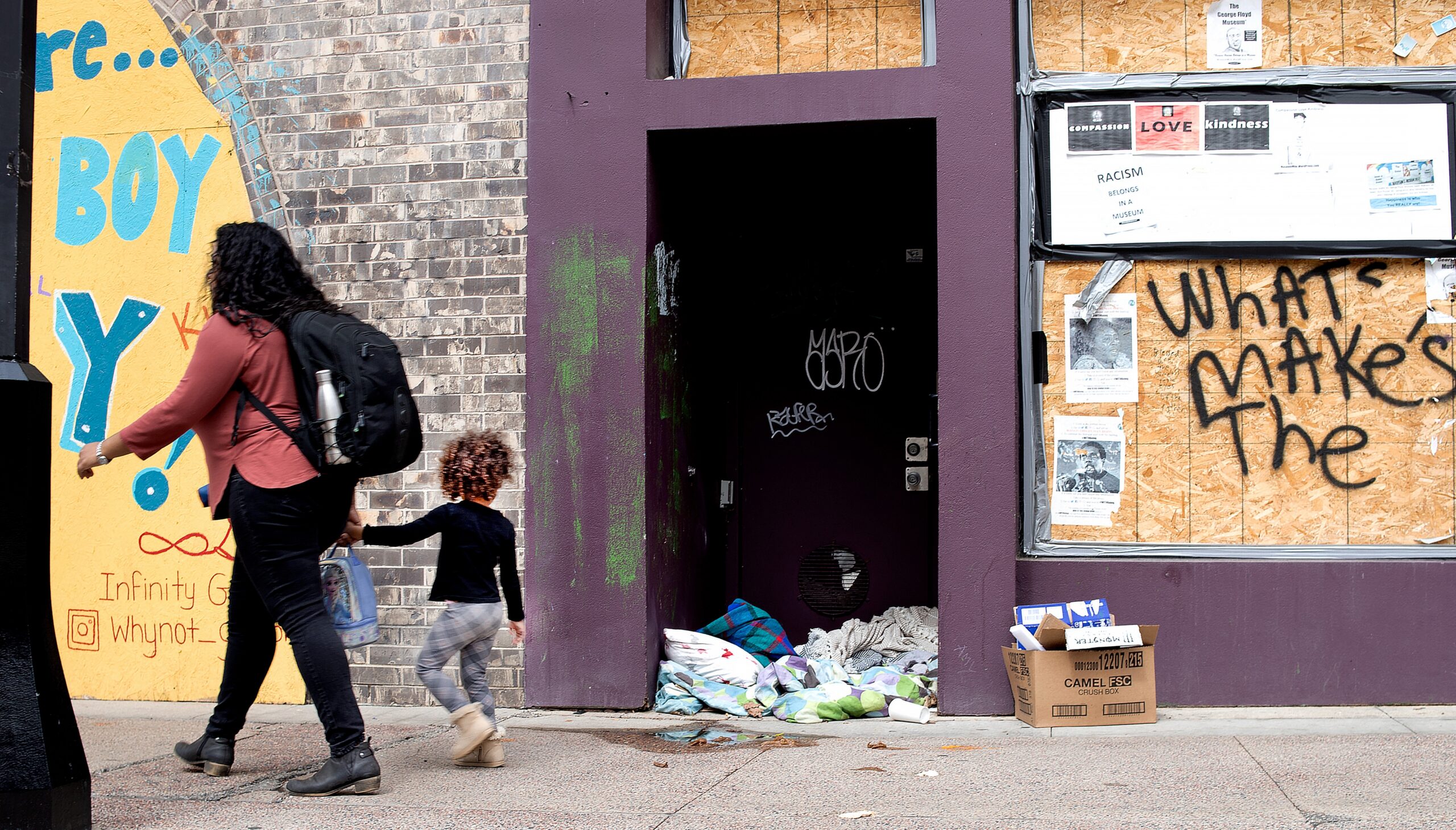 A woman and child pass by an abandoned storefront on State Street in Downtown Madison