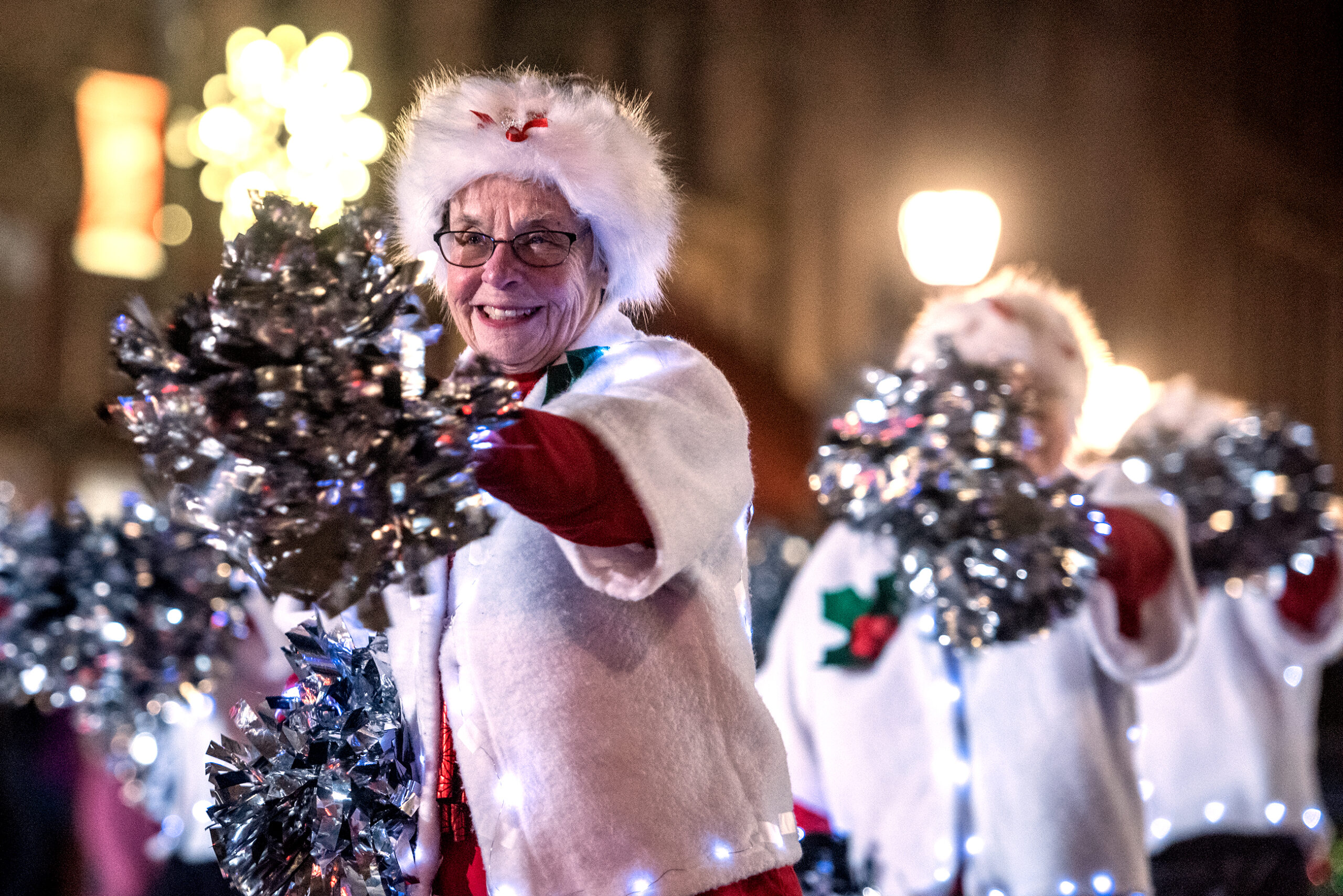 Women in white winter clothing perform with silver poms.