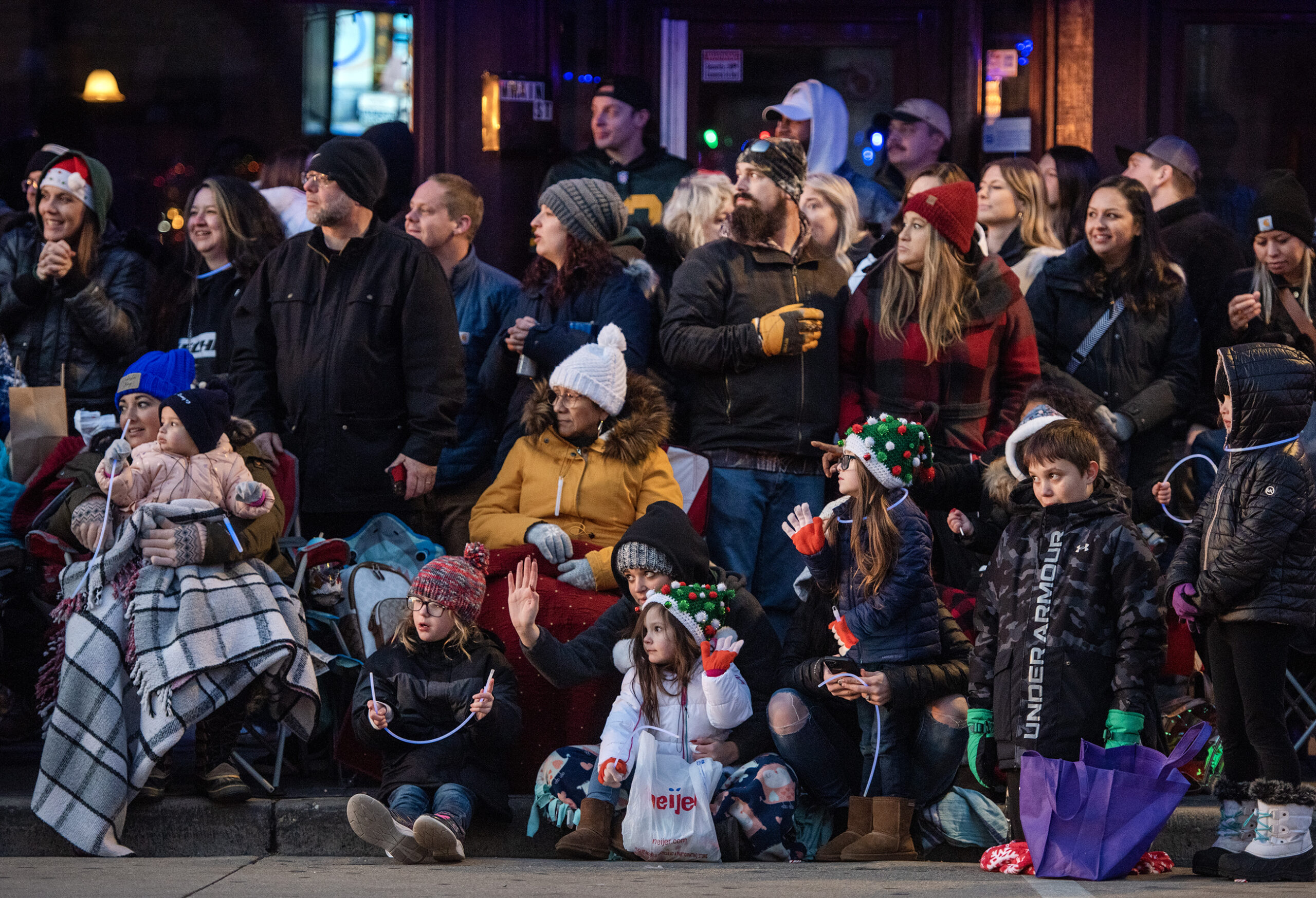 A crowd of parade attendees gather together wearing winter gear.