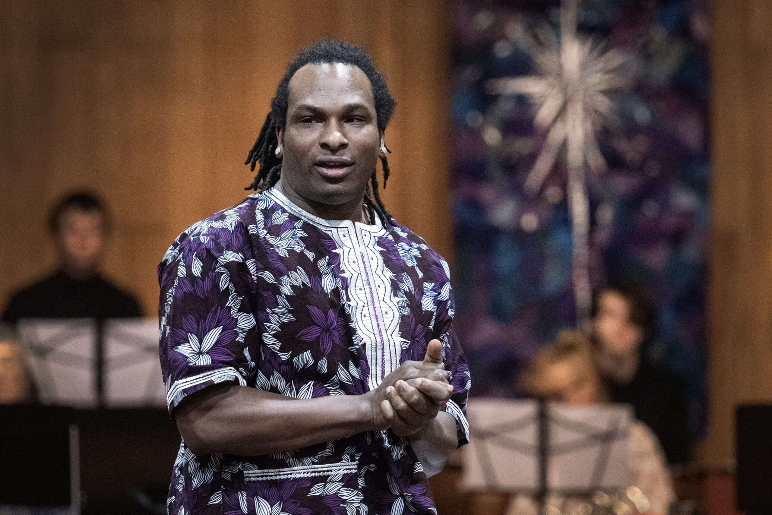 Dayvin Hallmond stands in front of the musicians and faces the crowd.