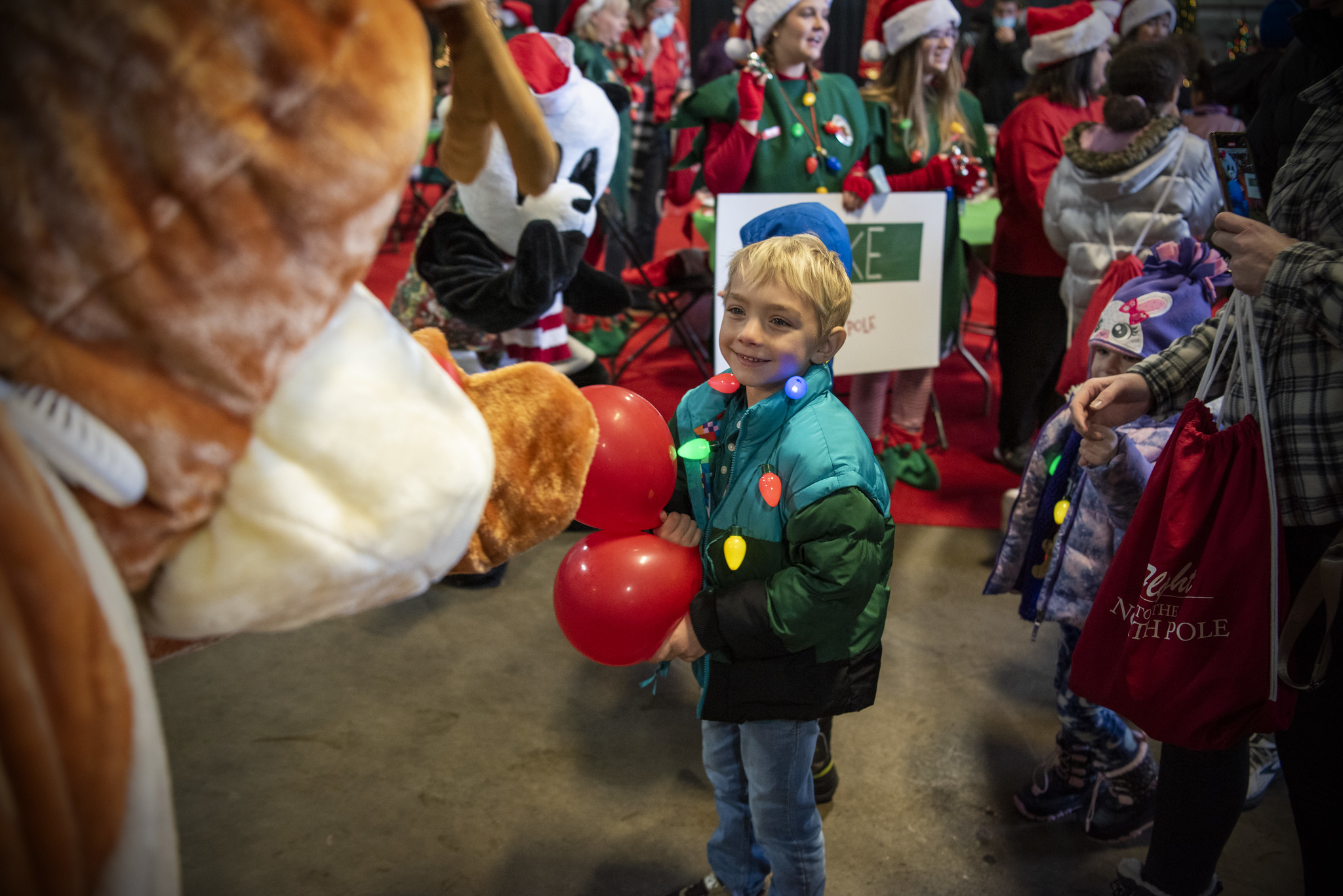 A child smiles as he is greeted by a reindeer.