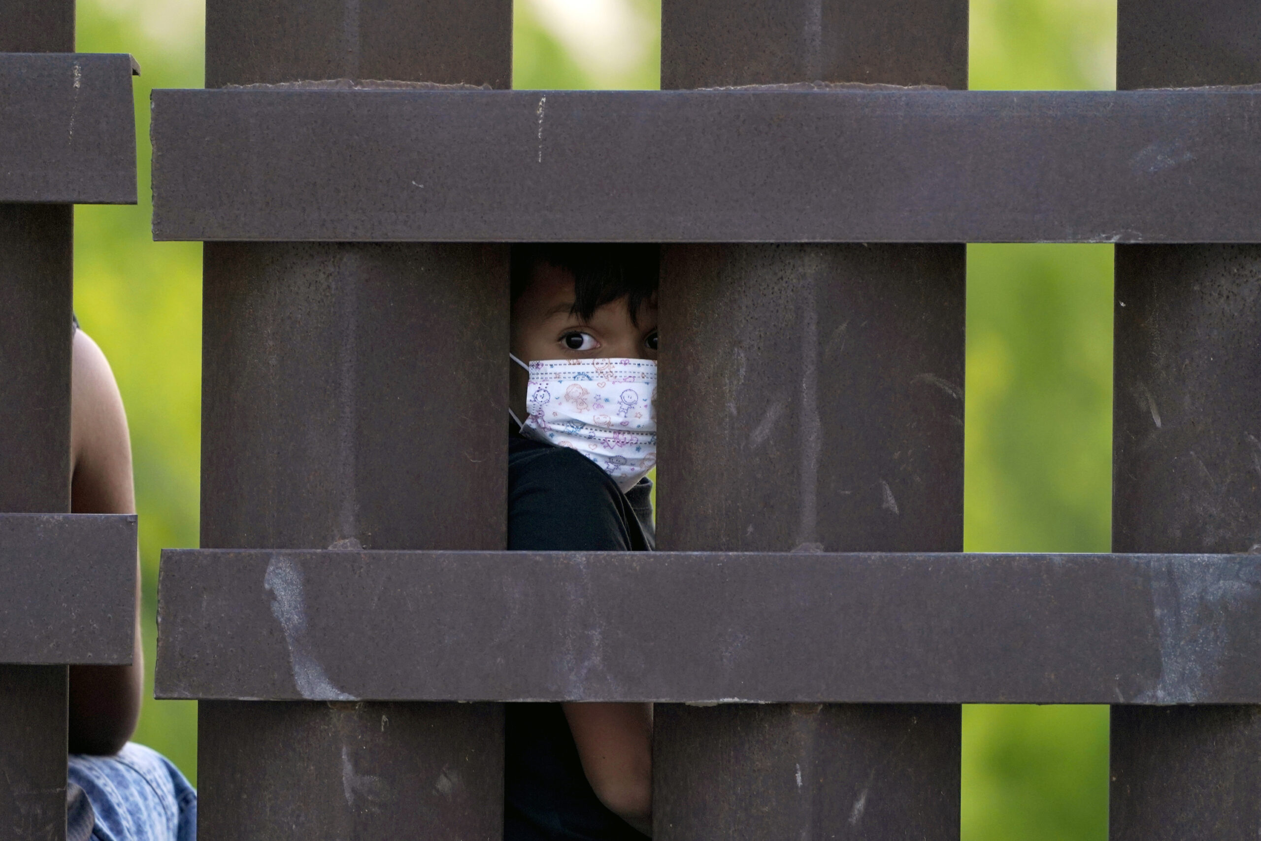 A child peeks through the U.S.-Mexico border metal wall