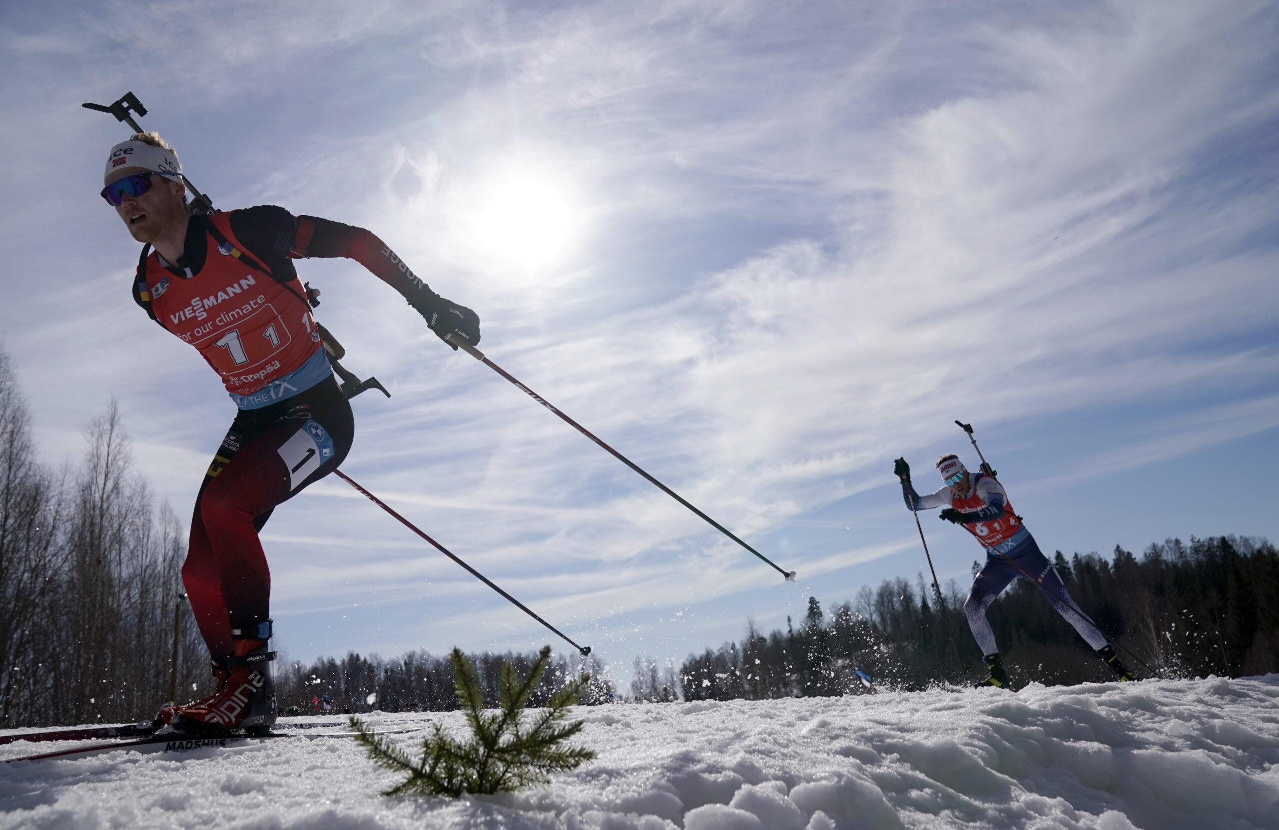 A biathlete cross country skiis with a rifle on their back