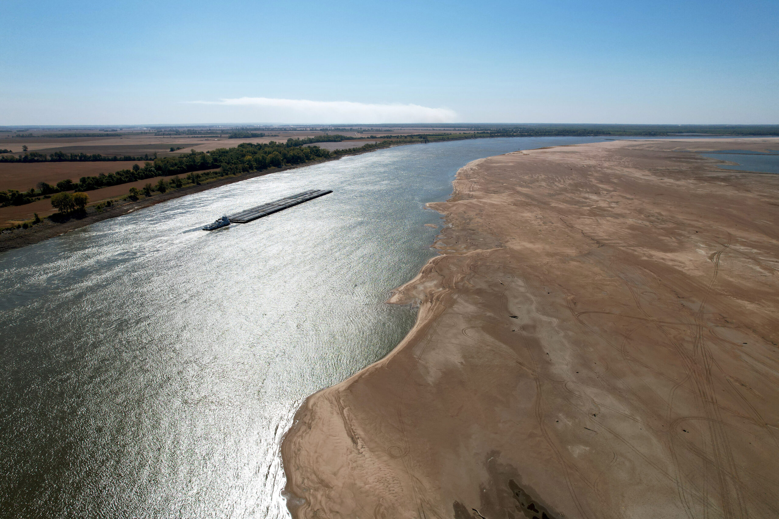 a barge maneuvers its way down the normally wide Mississippi River where it has been reduced to a narrow trickle
