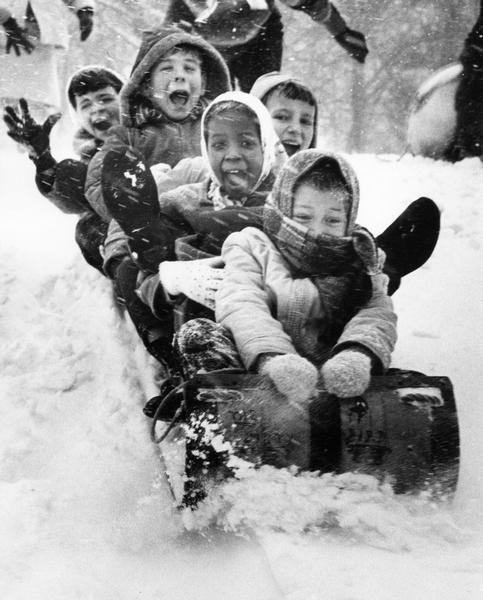 A winter scene with excited children on a toboggan, circa 1975