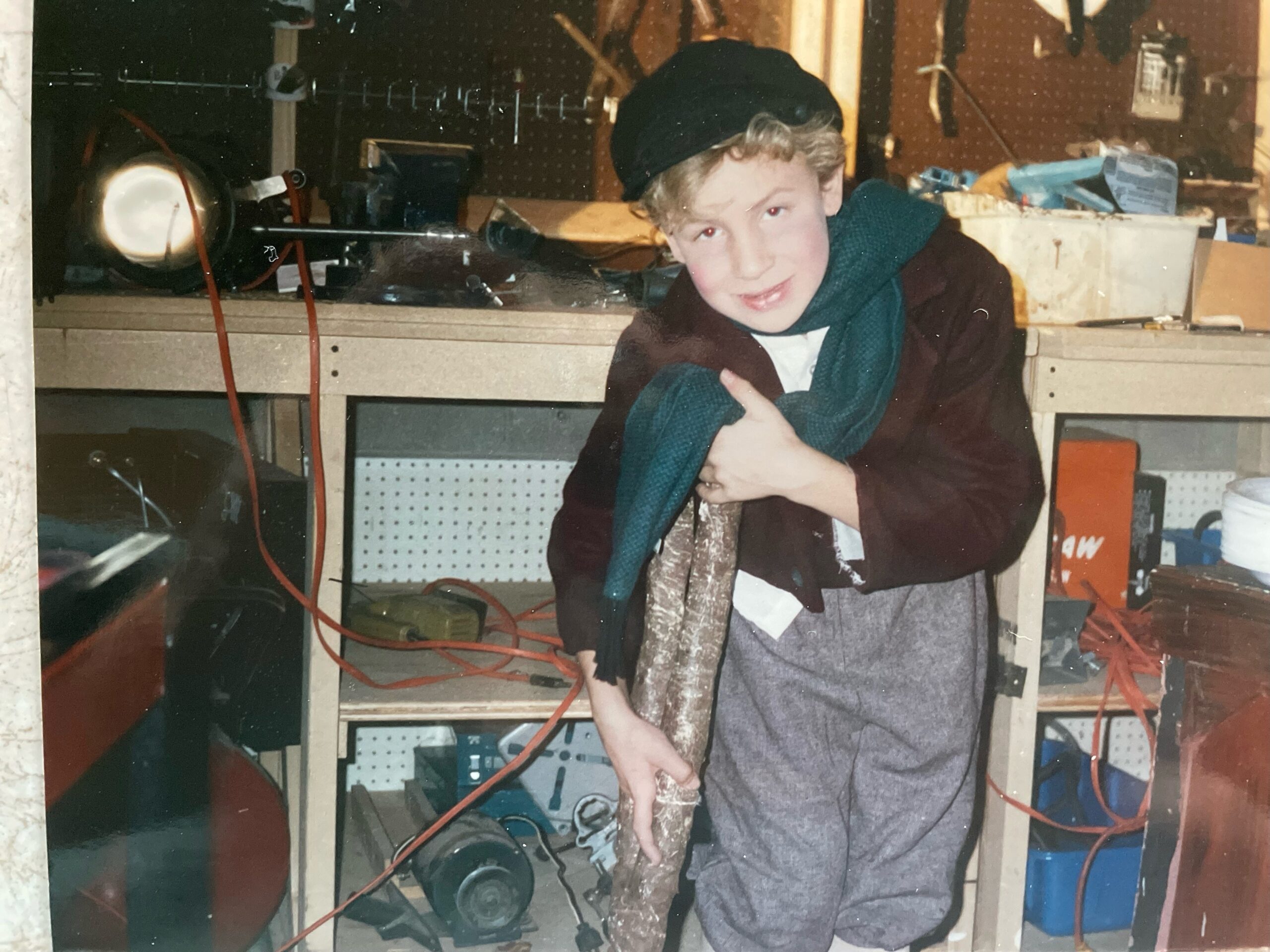 A boy dressed for the role of Tiny Tim leans on a stick as a cane