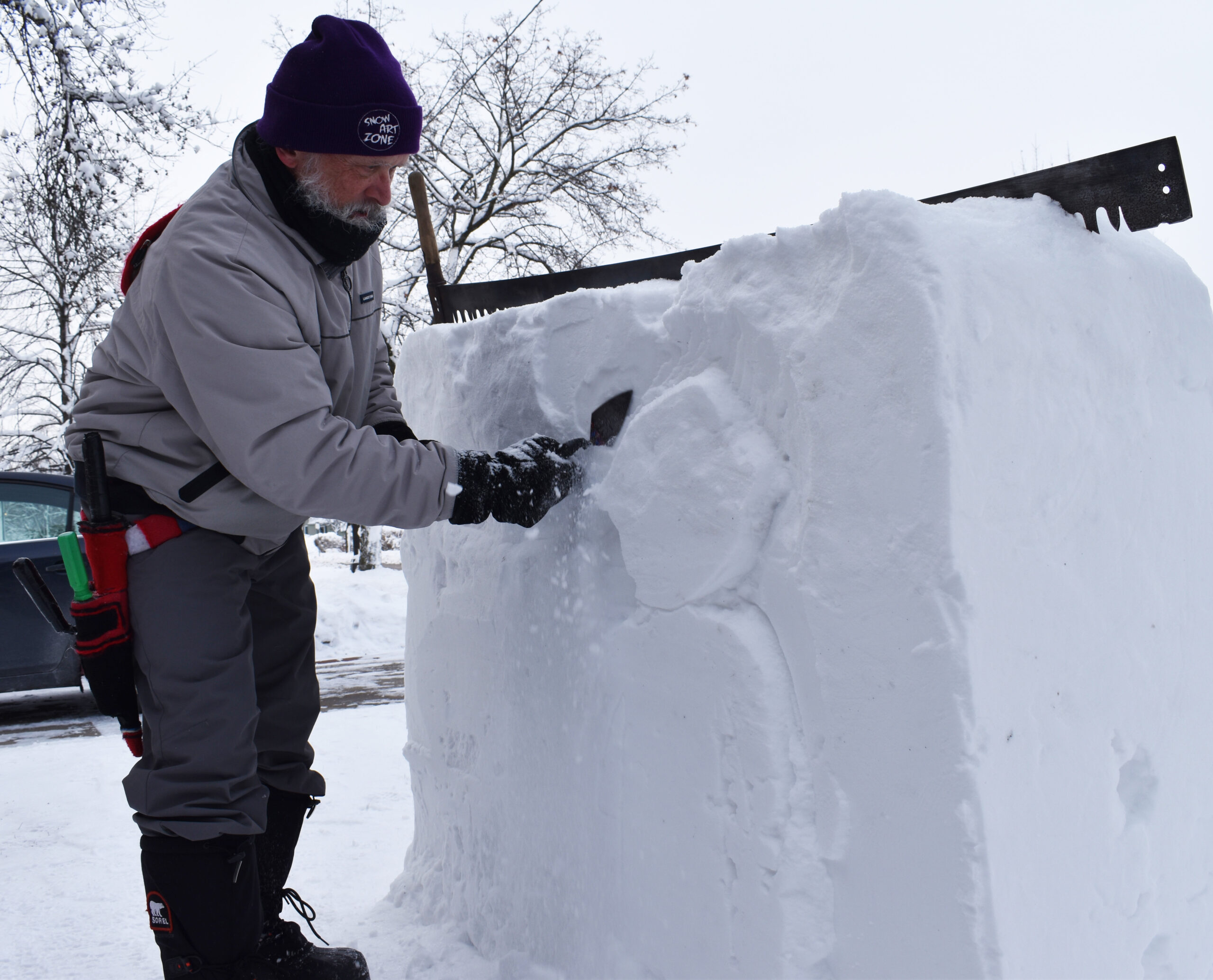 Snow sculptor Jef Schobert works with a trowel on one of his carvings in his front yard in Stevens Point.