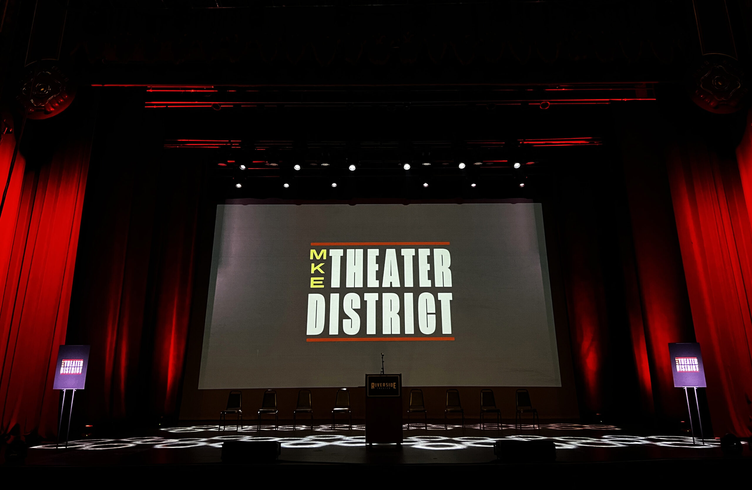 the Milwaukee Theater District logo is projected on a screen at a theater in downtown Milwaukee.
