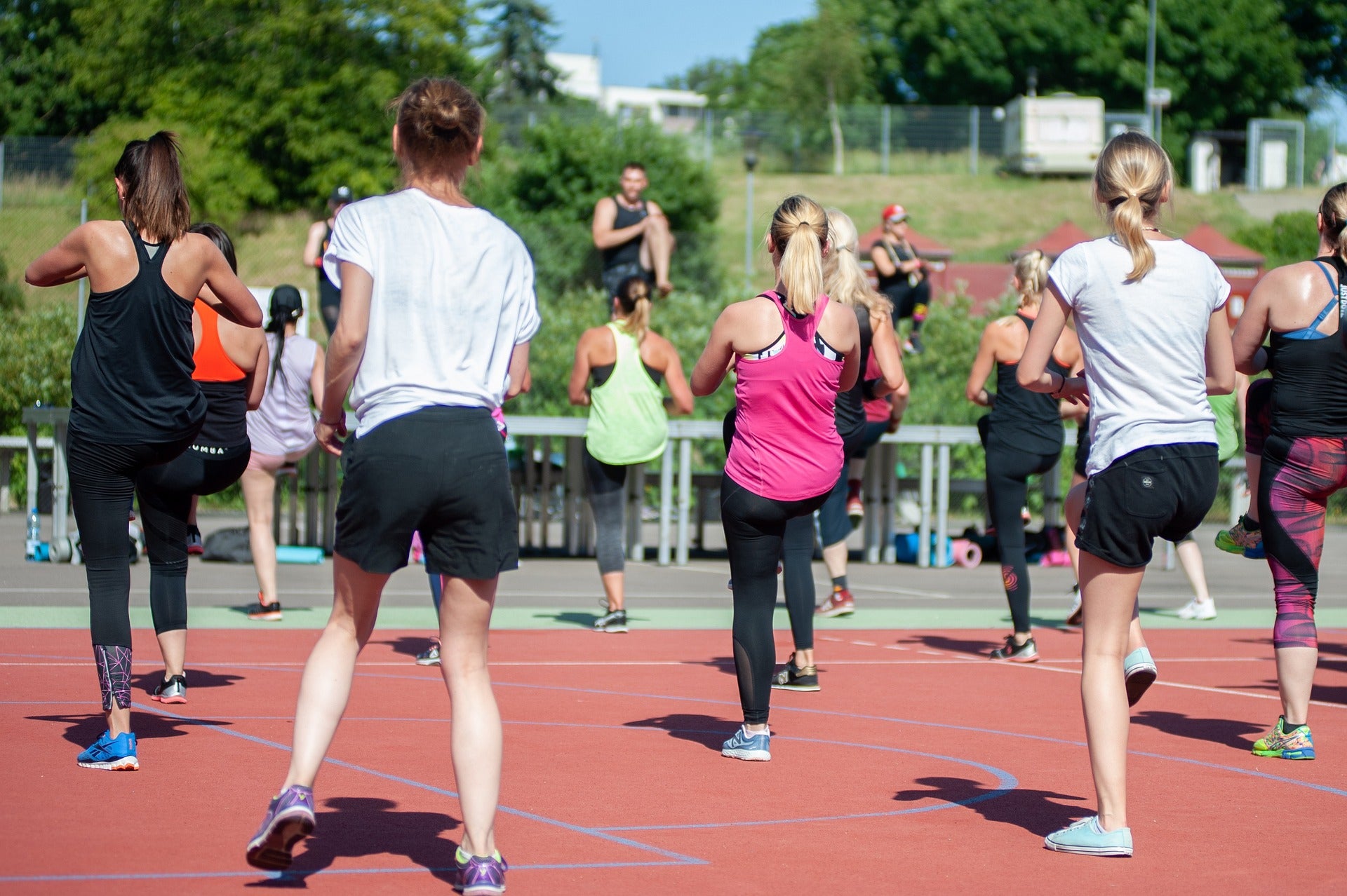 A people dance in lines on an outdoor court during a Zumba class.