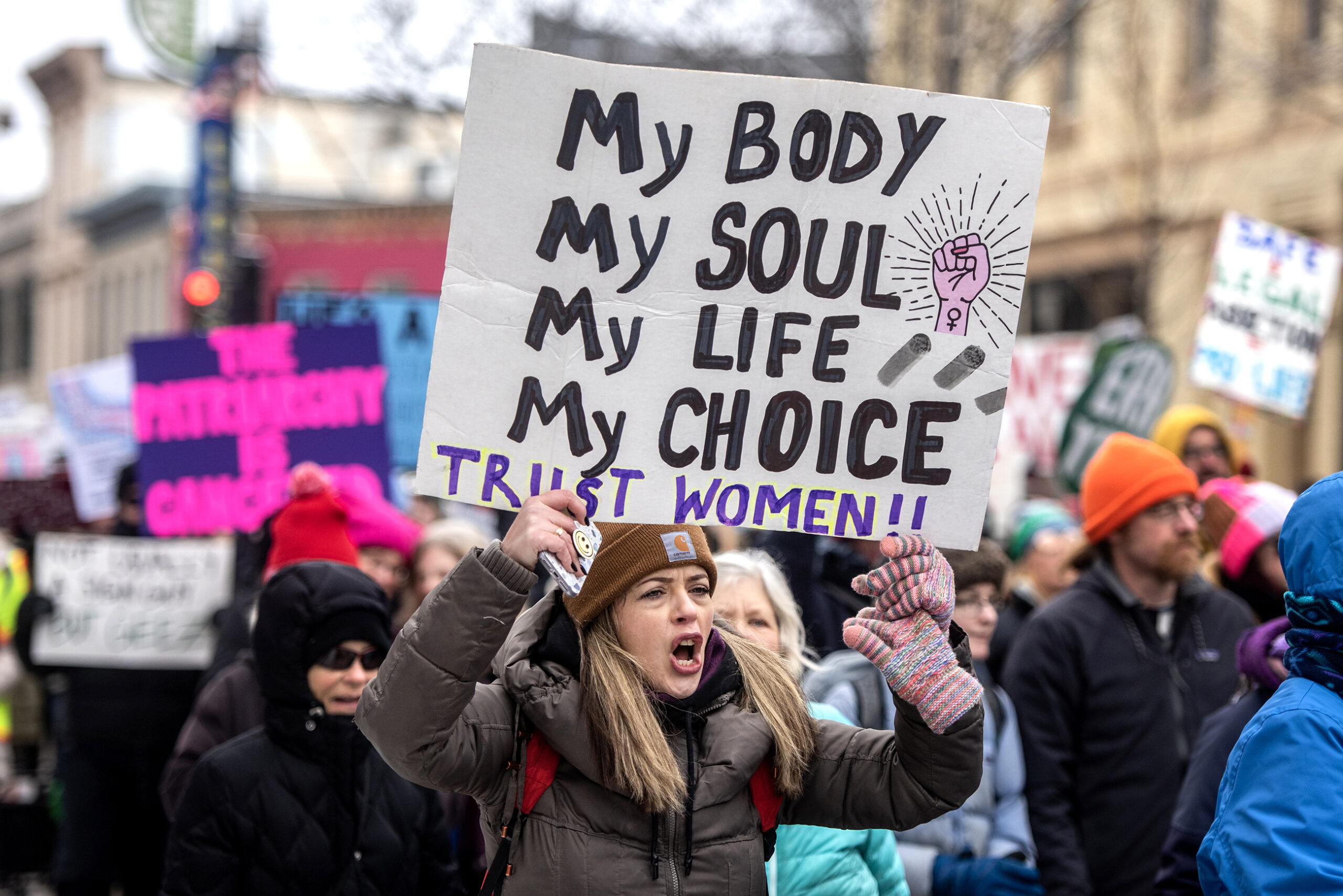 A protester's sign says "My body, my soul, my life, my choice. Trust women!!"