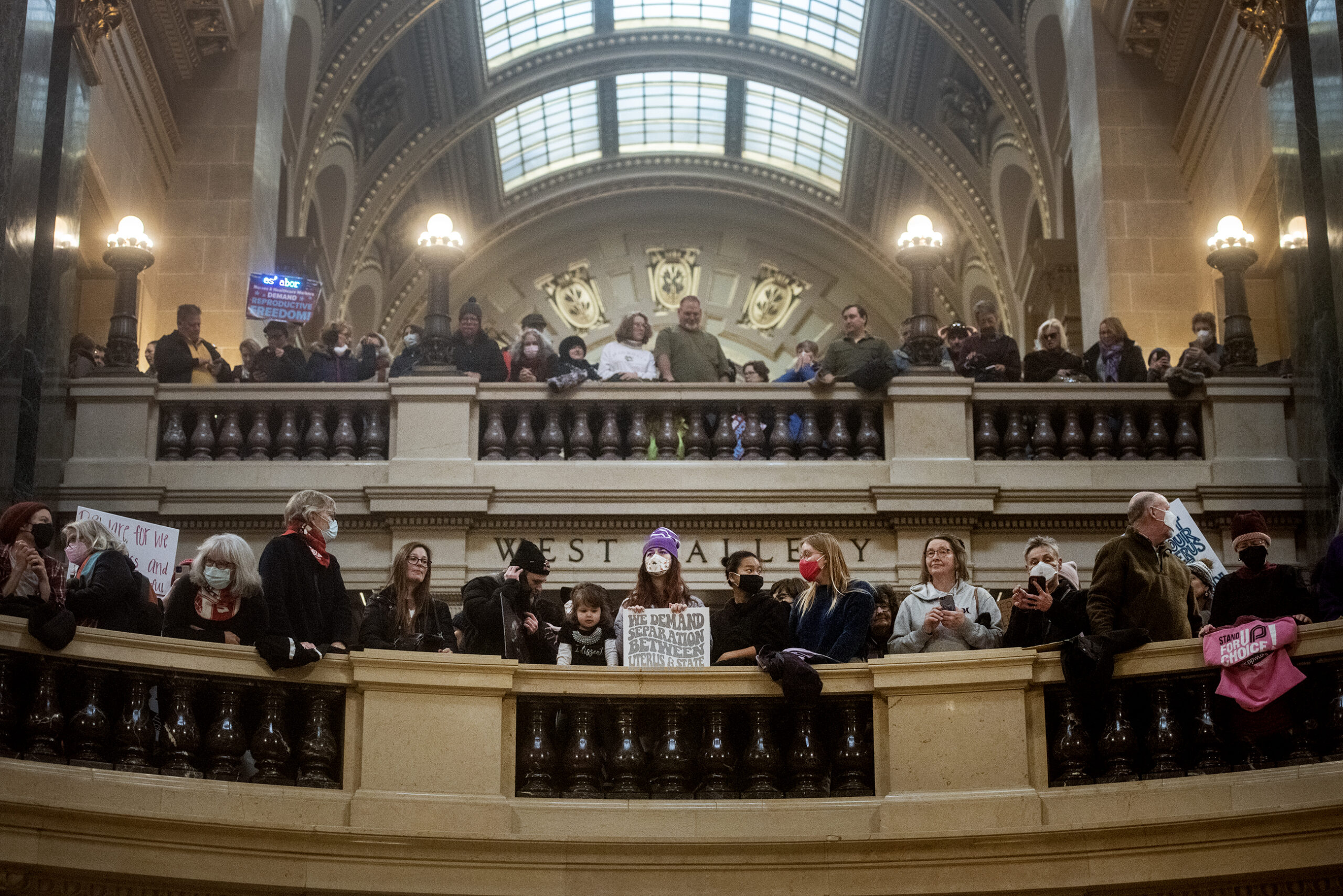 People lean up against the railing in the Wisconsin state Capitol.