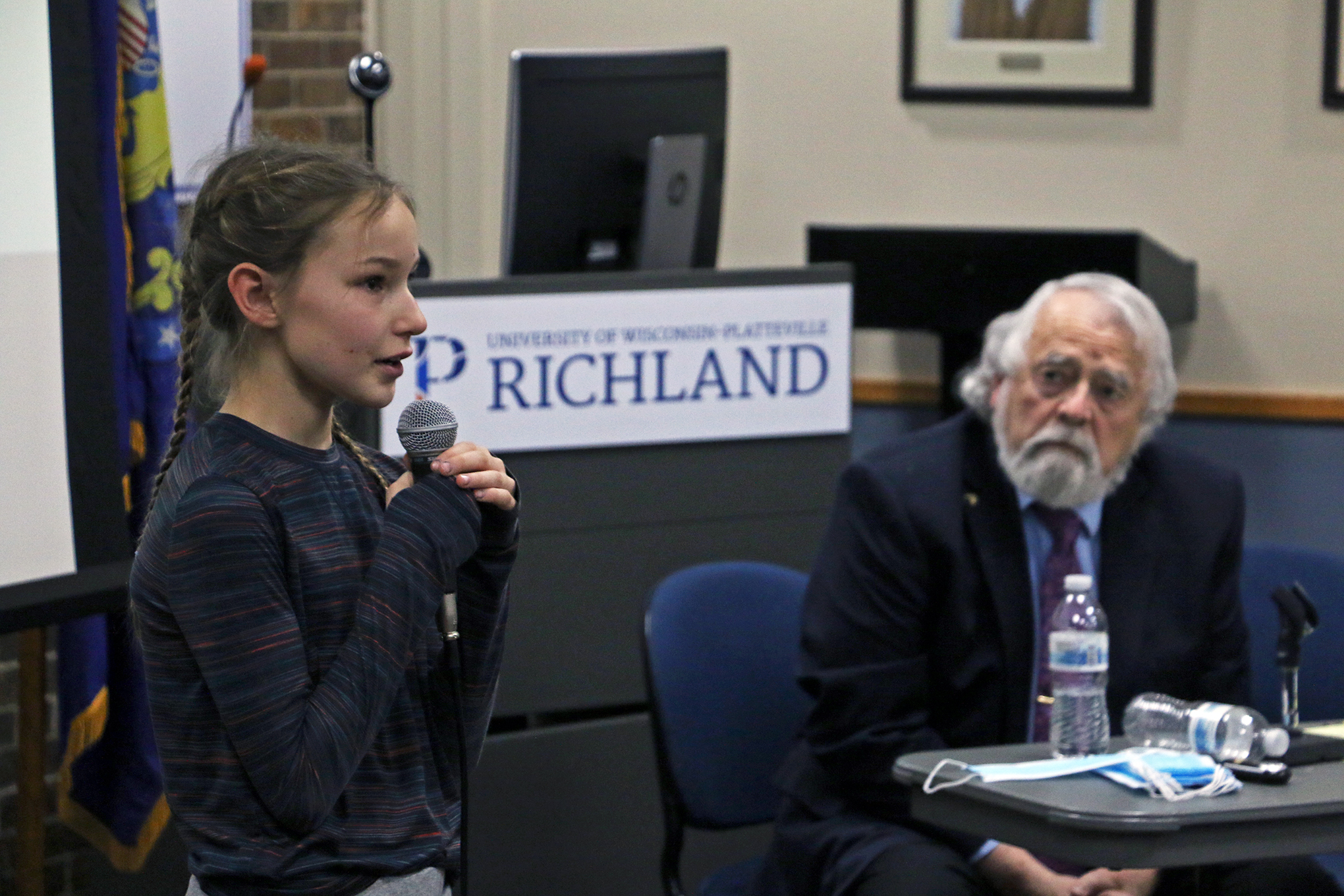 A young girl speaks into a microphone at a town hall meeting aimed at stopping the planned end of college classes at UW-Platteville Richland