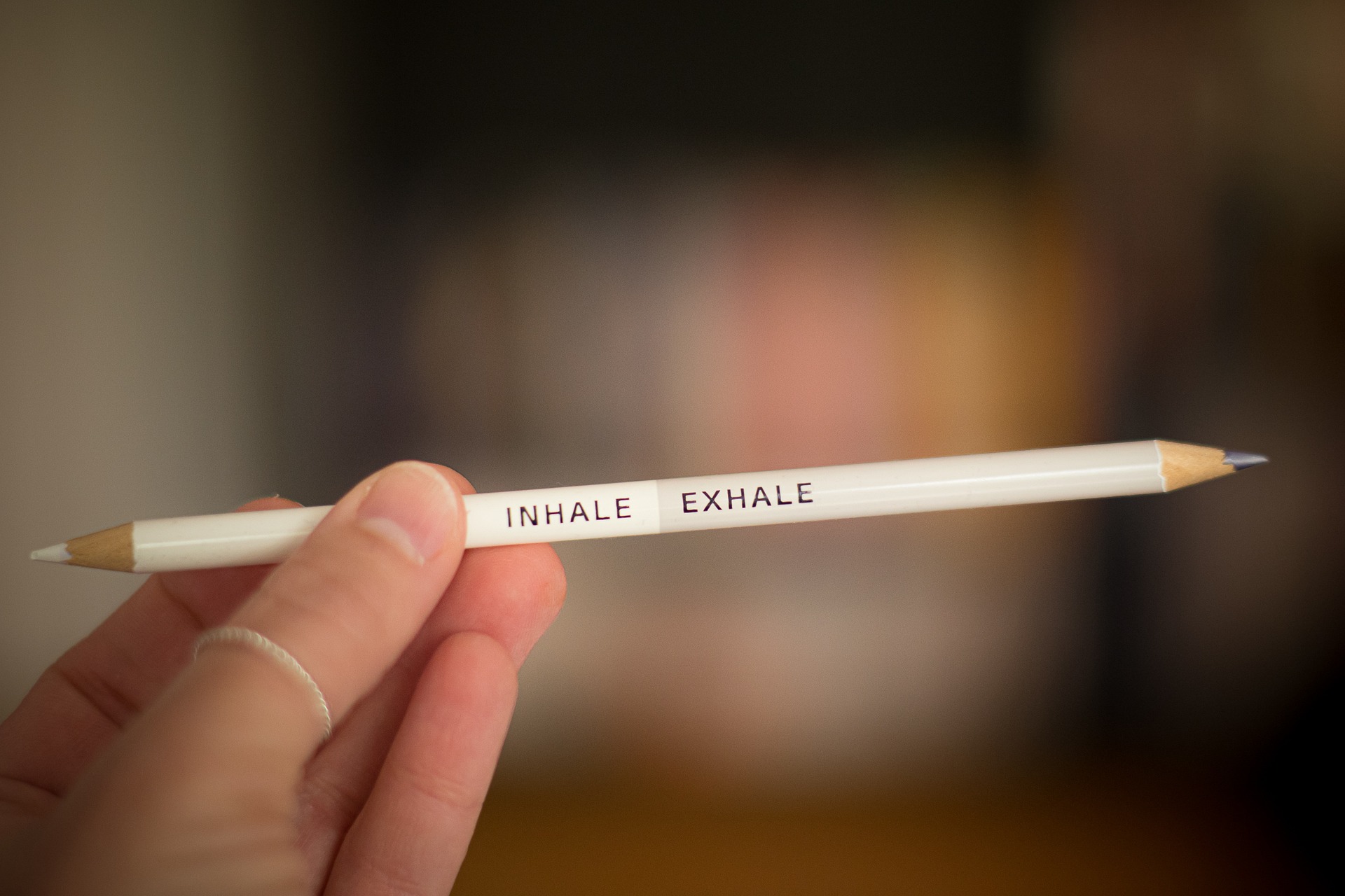A hand holds a white pencil that reads "inhale" and "exhale."