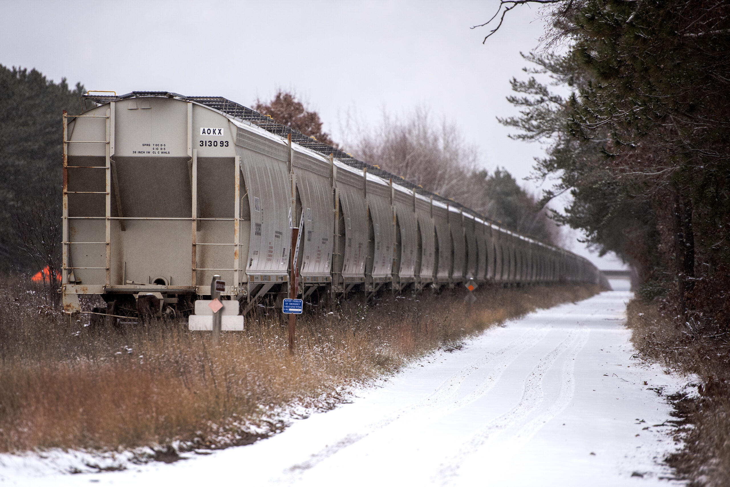 Gray metal train cars form a long line on a winter day.