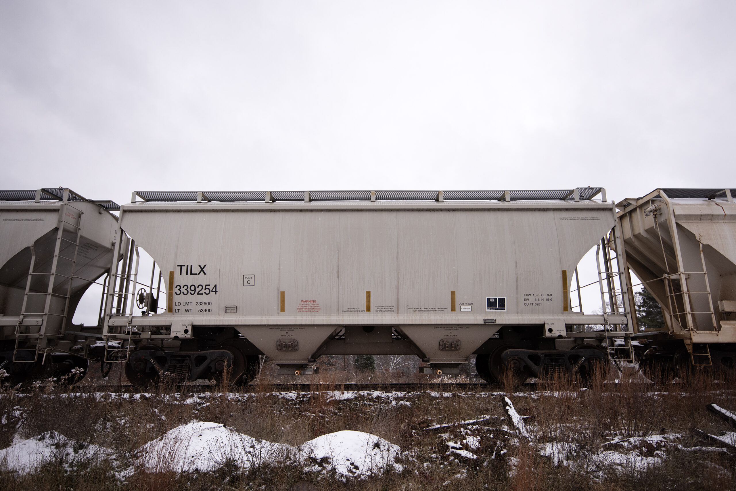 Gray metal train cars form a long line on a winter day.