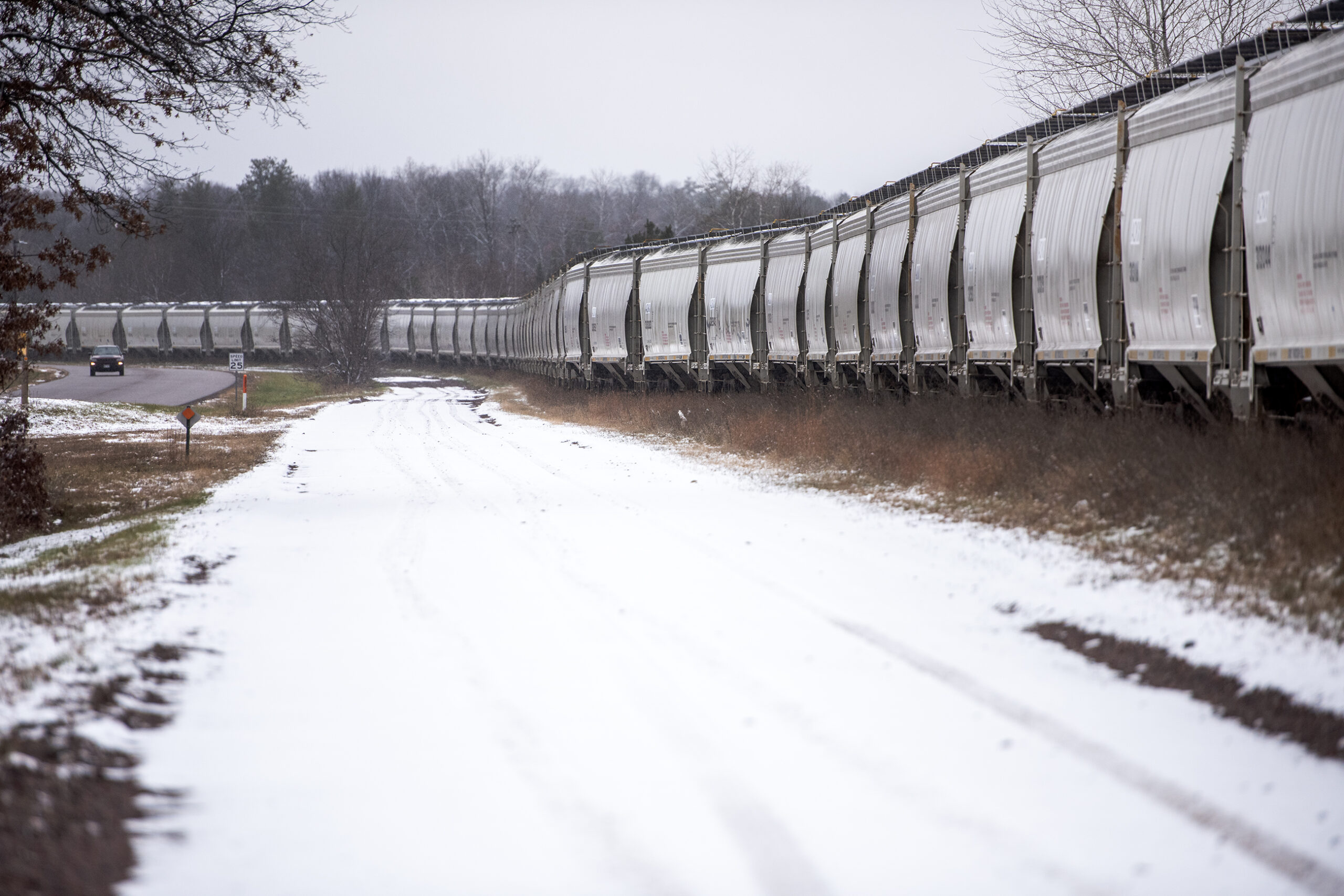 Gray metal train cars form a long line on a winter day.