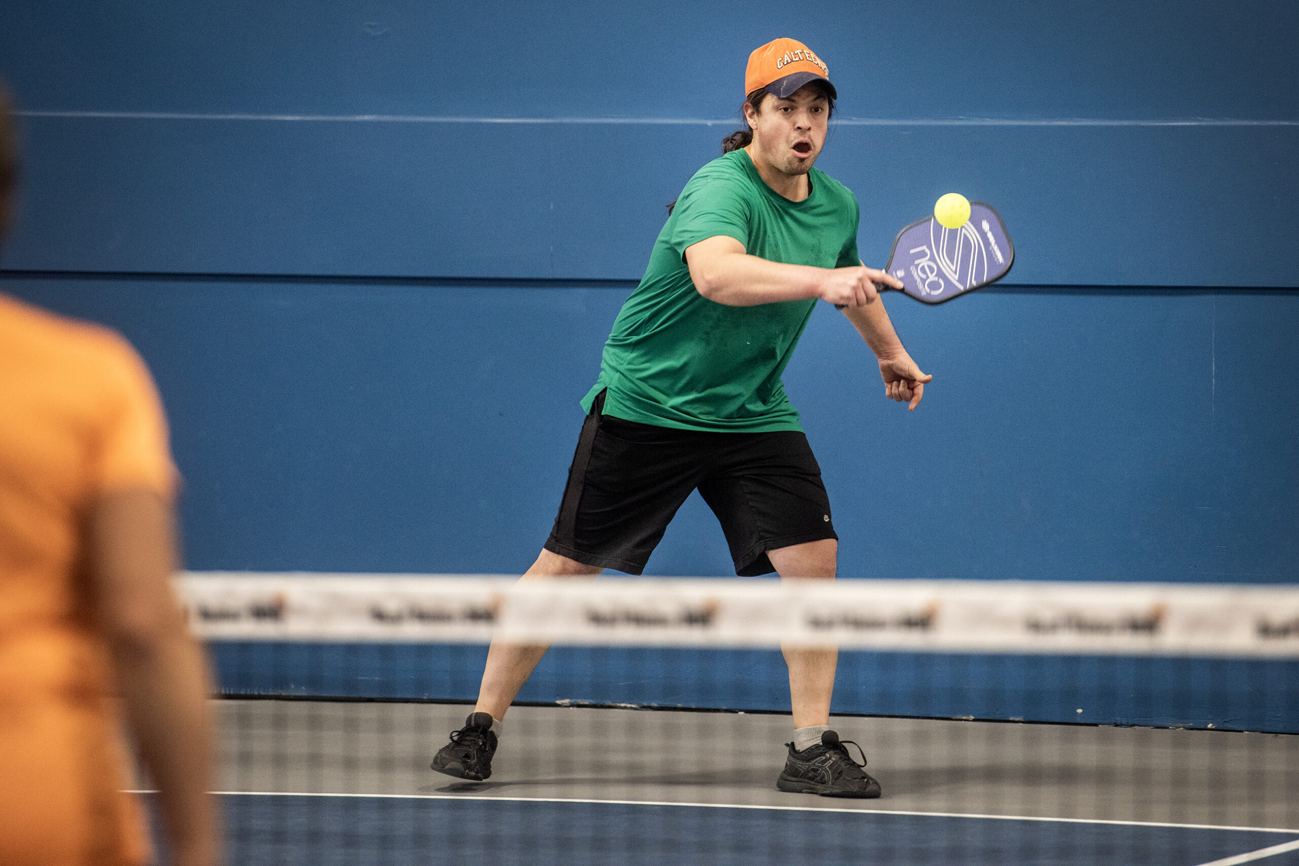 A man uses a paddle to hit a yellow ball.