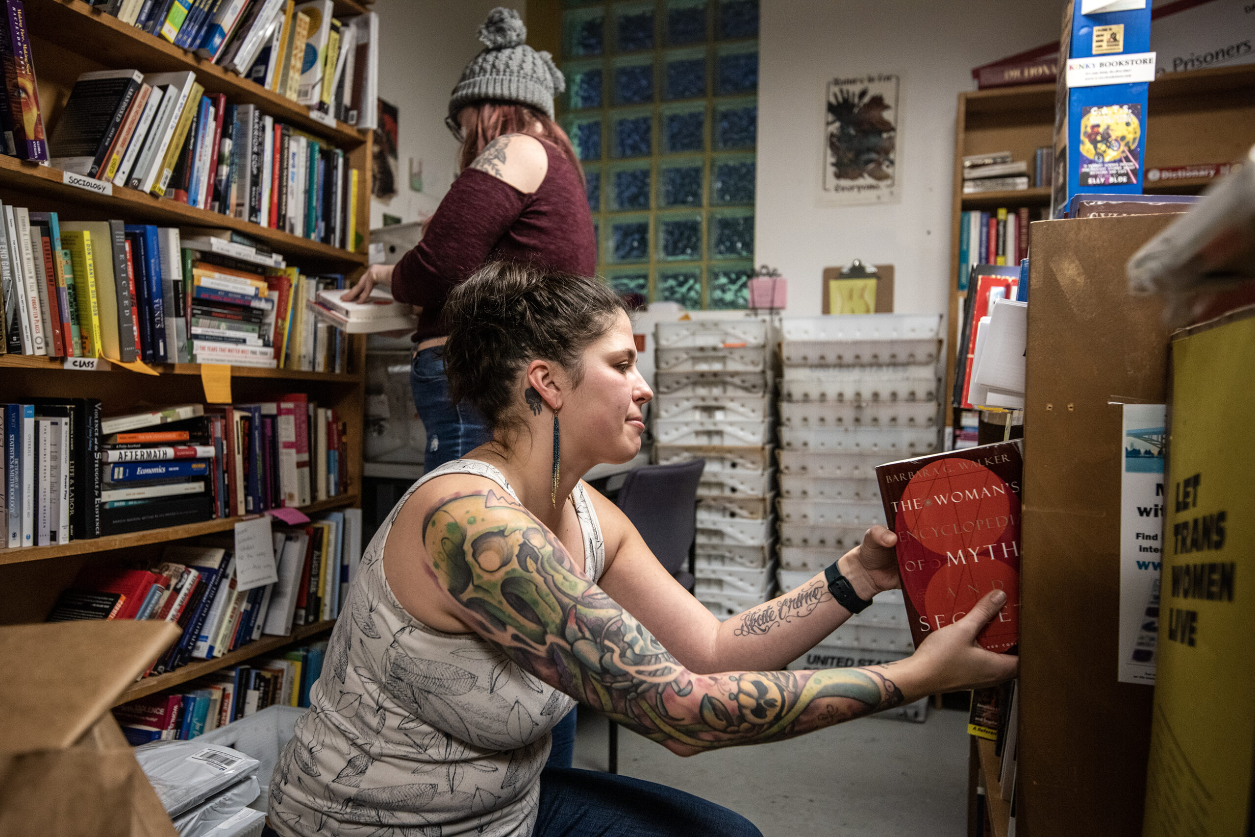 Two volunteers go through bookshelves filled with books.