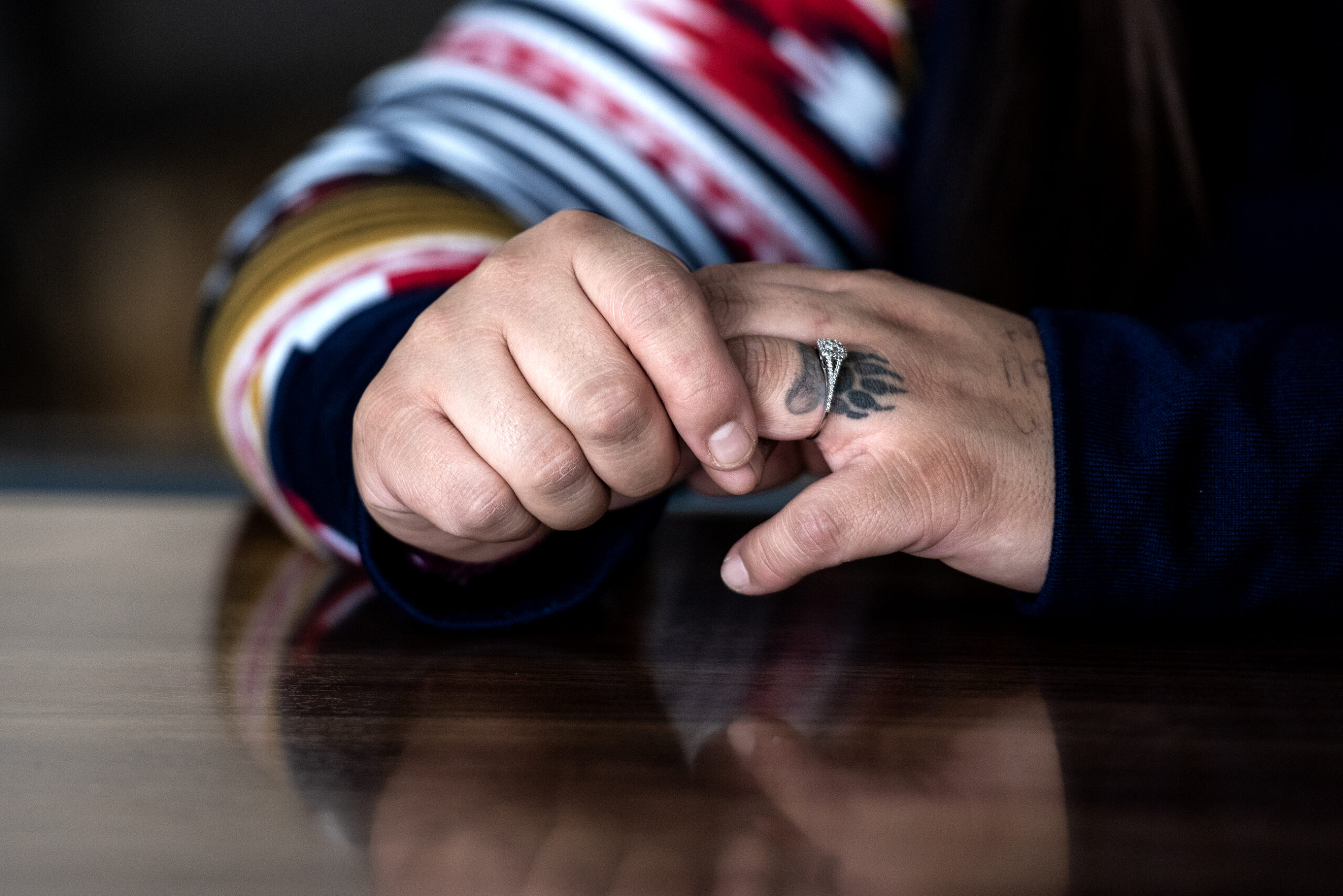 Lydi Dodge holds her hands together. She wears a wedding ring on her tattooed fingers.