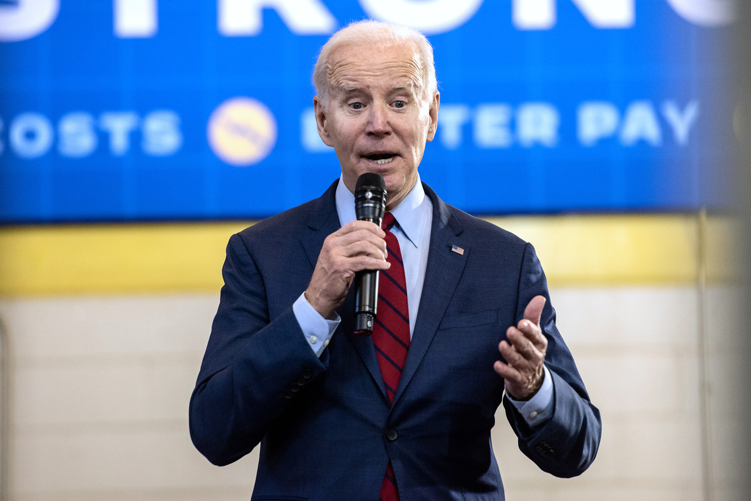 President Joe Biden gestures as he speaks into a microphone.