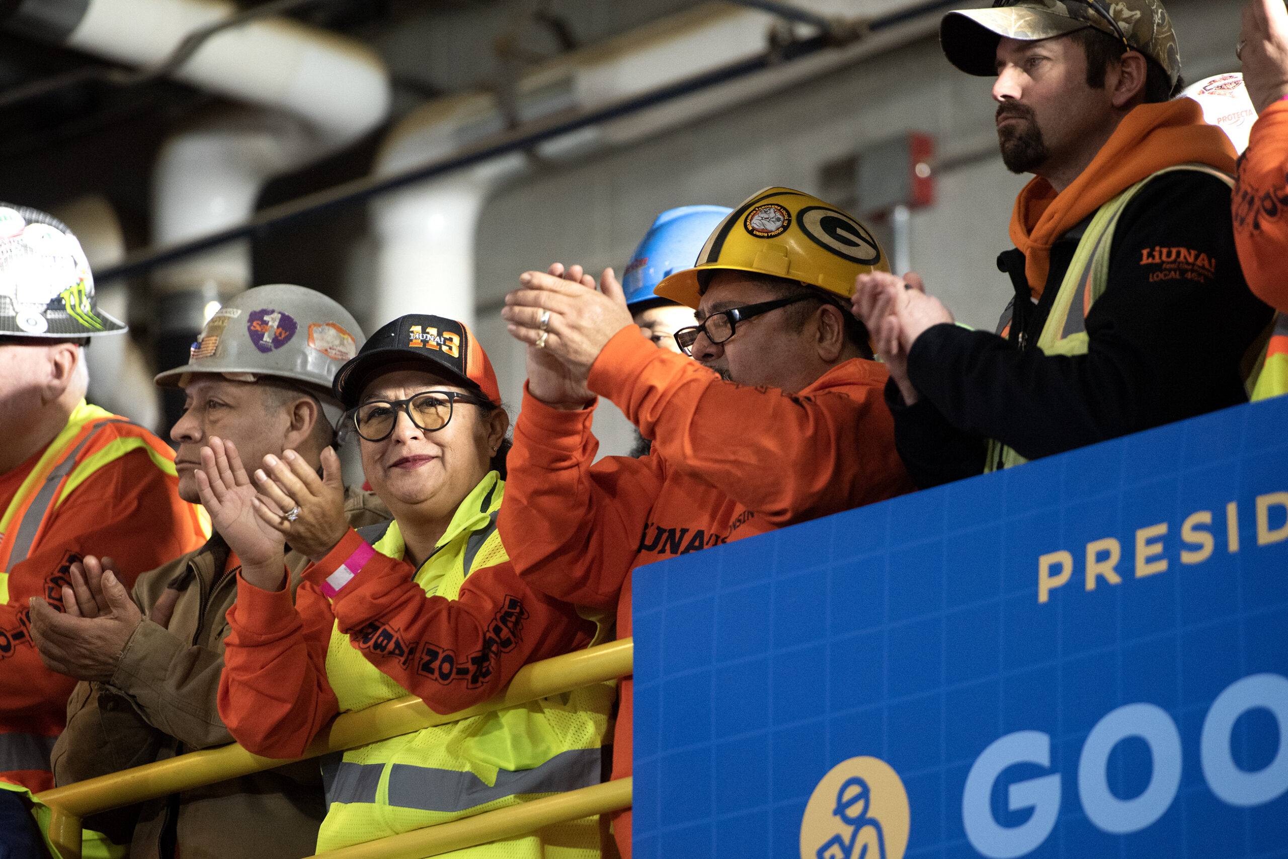 Workers in neon vests and hard hats applaud.