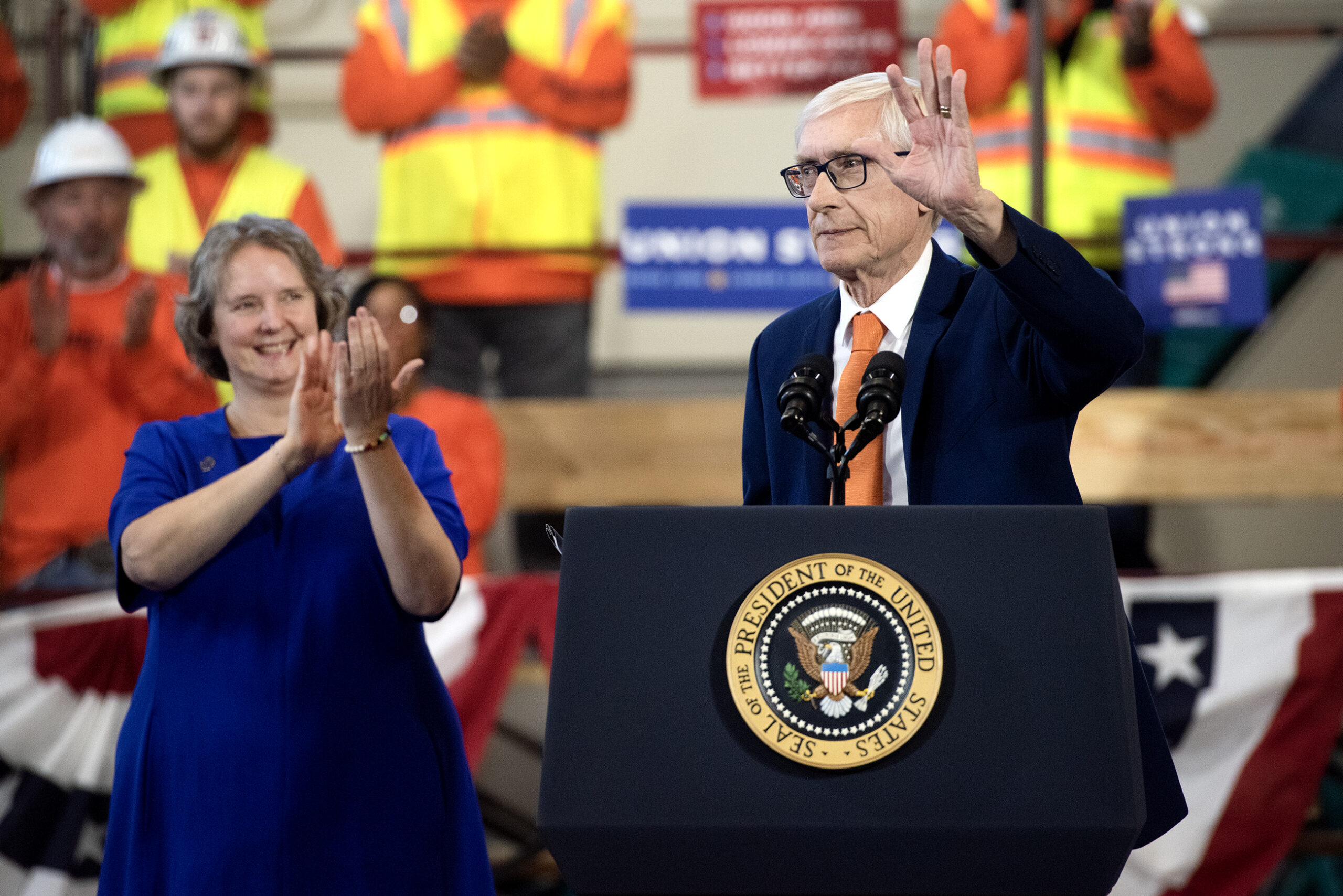 Gov. Tony Evers waves as Mayor Rhodes-Conway applauds.