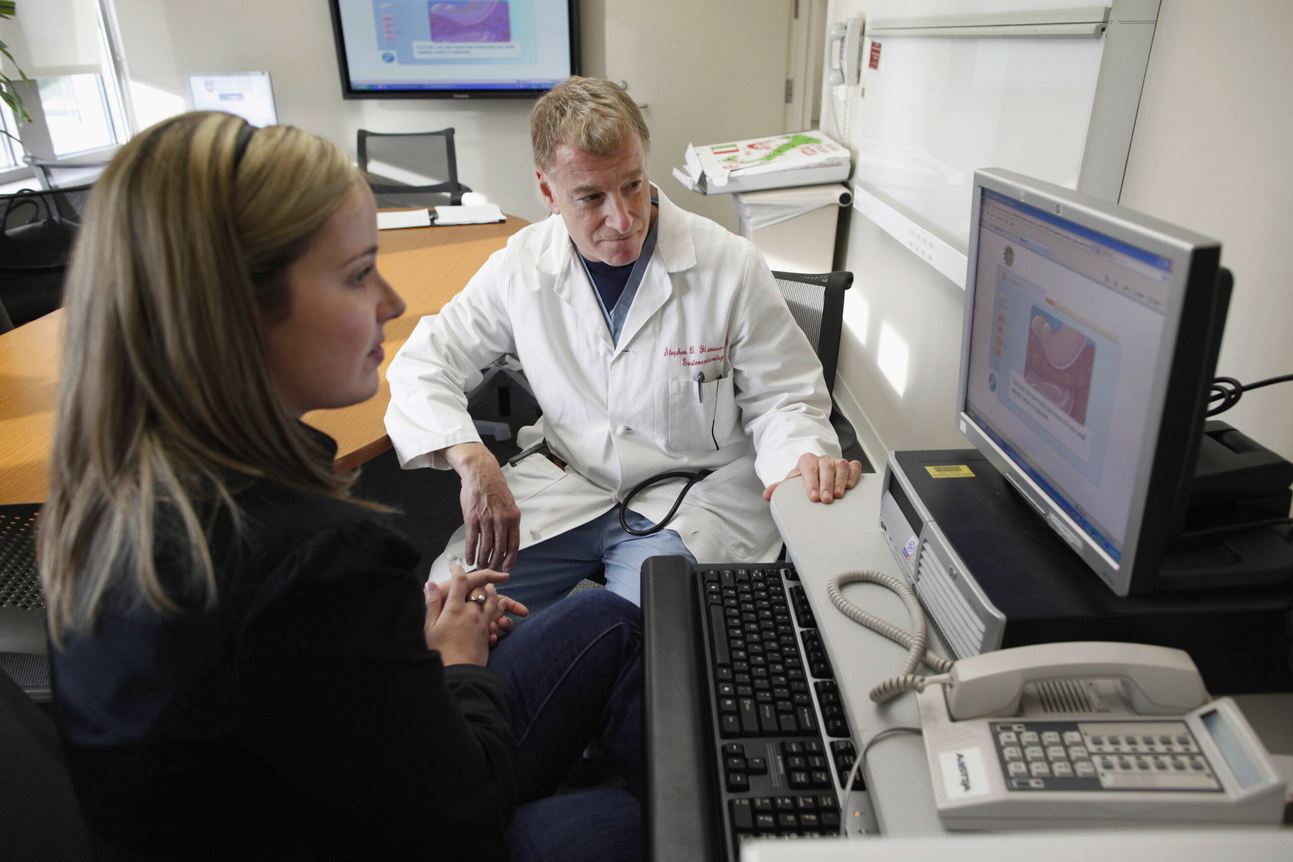 A woman looks at a computer screen with a doctor