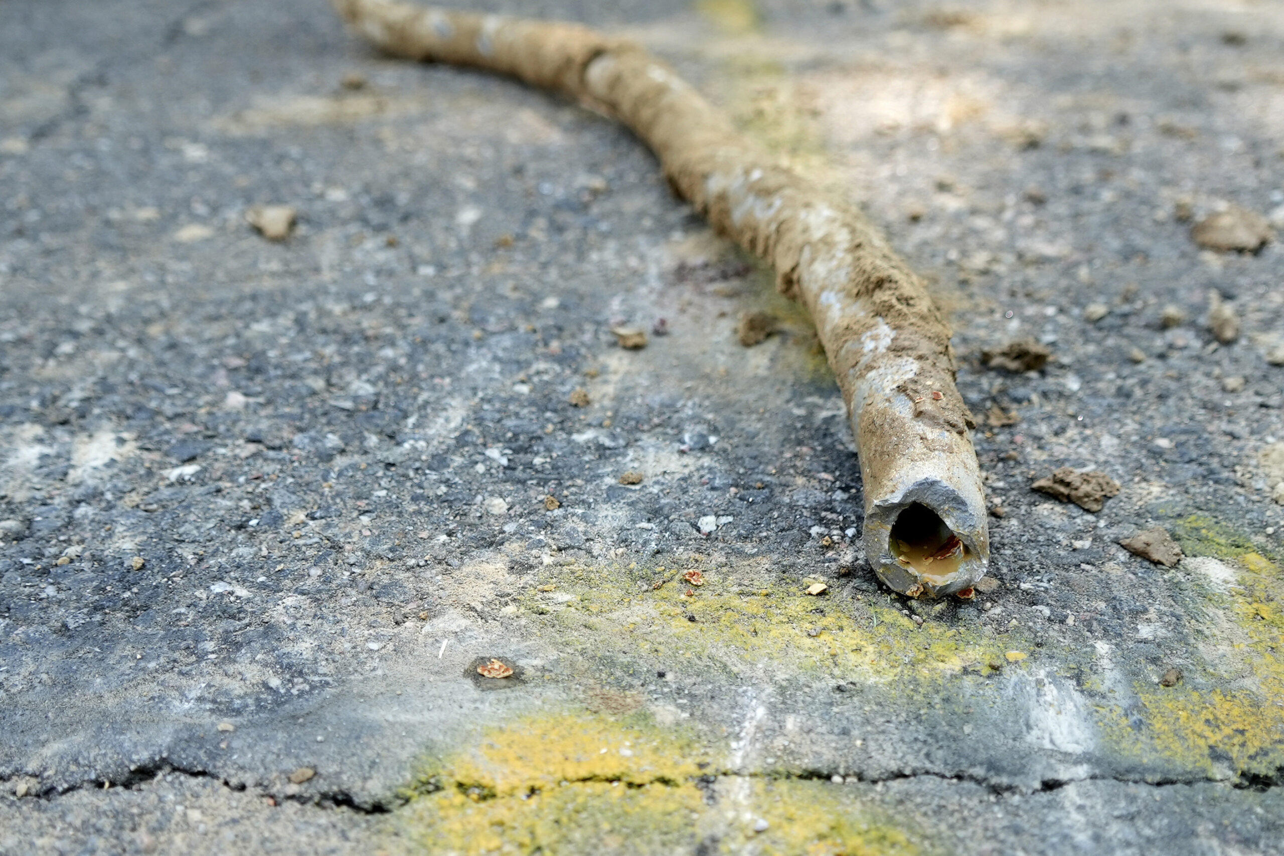 An old lead pipe lying on blacktop
