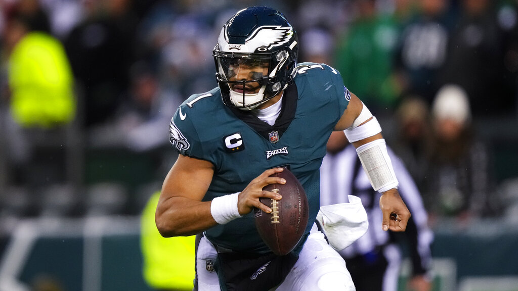 Philadelphia Eagles quarterback Jalen Hurts runs with the ball in the middle of a game.