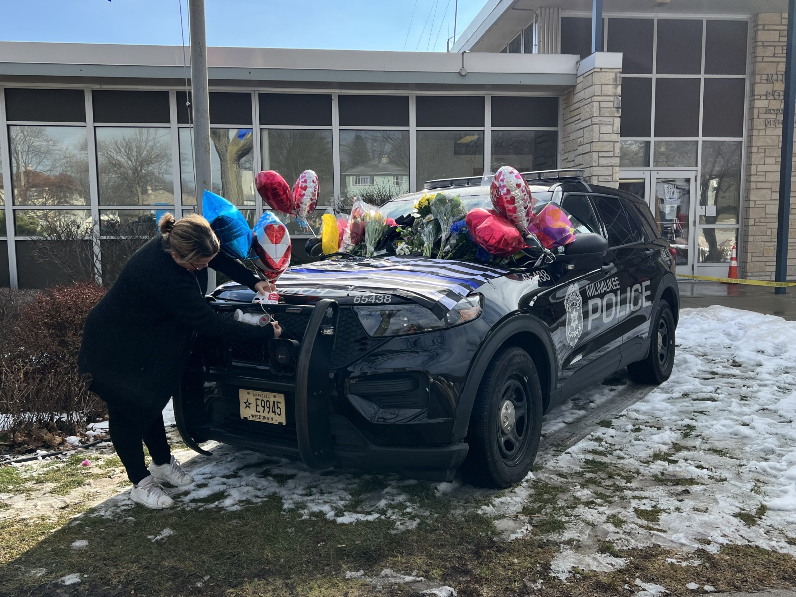 A Milwaukee police auxiliary officer places a balloon on a car dedicated to officer Peter Jerving