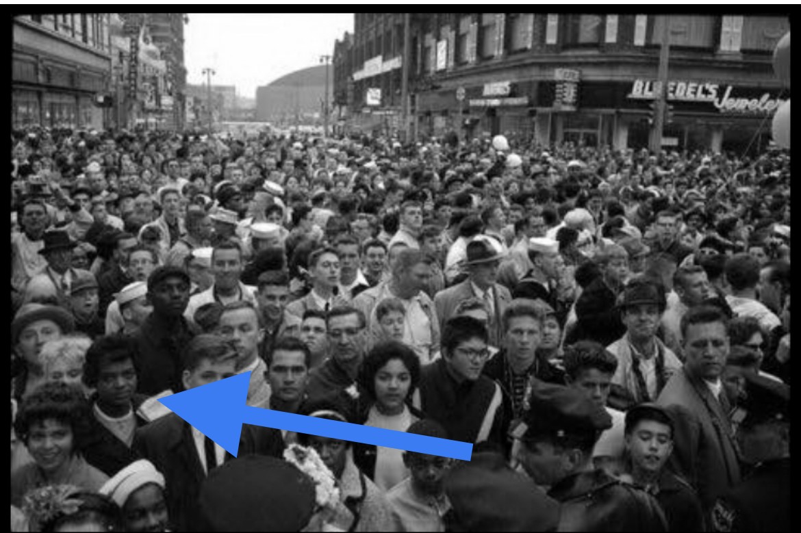 A black and white photo of a crowd at a protest, with a blue arrow pointing out Juanita Adams toward the front of the crowd