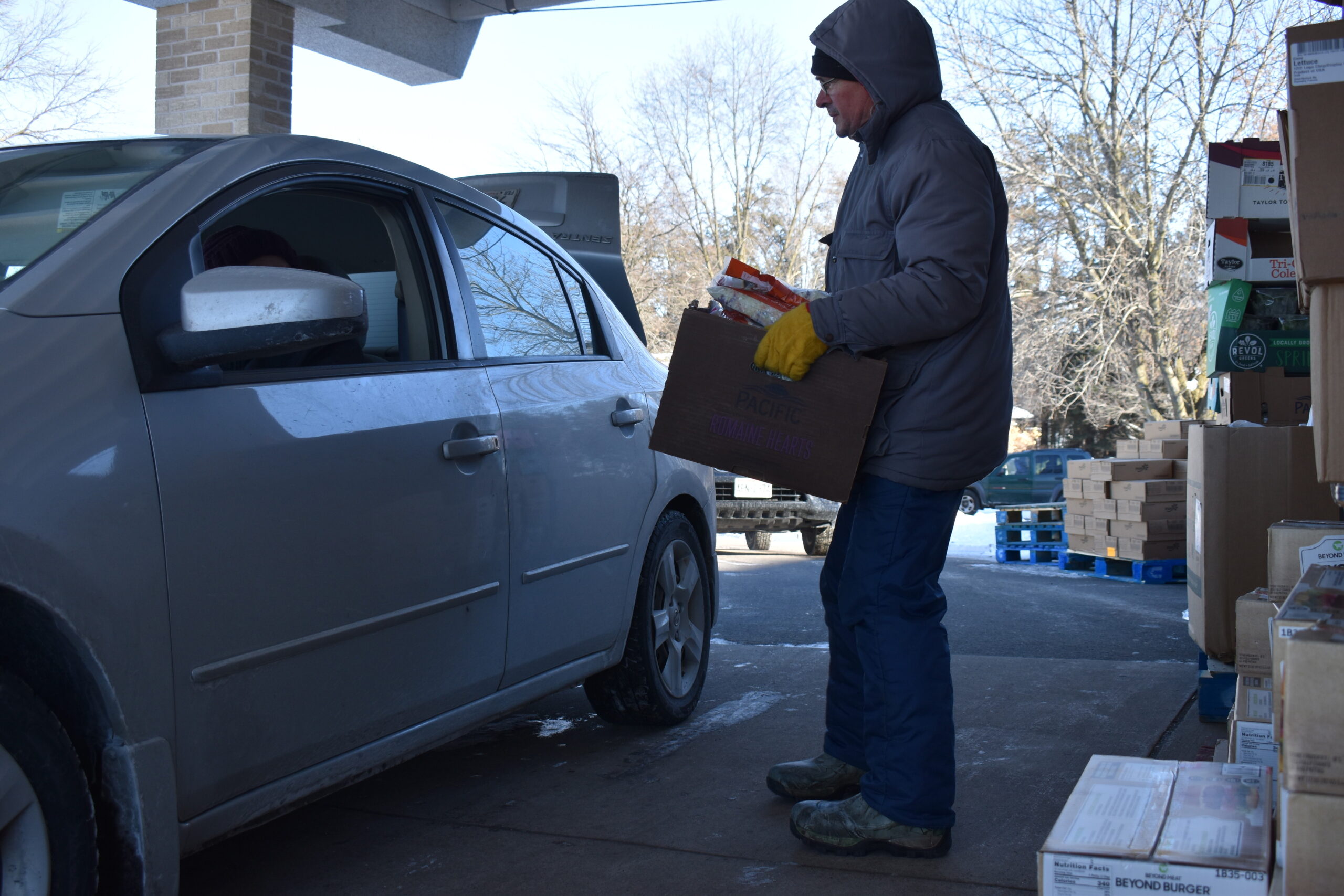 Tim Kapfhamer of St. Bernard's Catholic Church carries a box of food to the car of a social worker who will distribute it to rural families