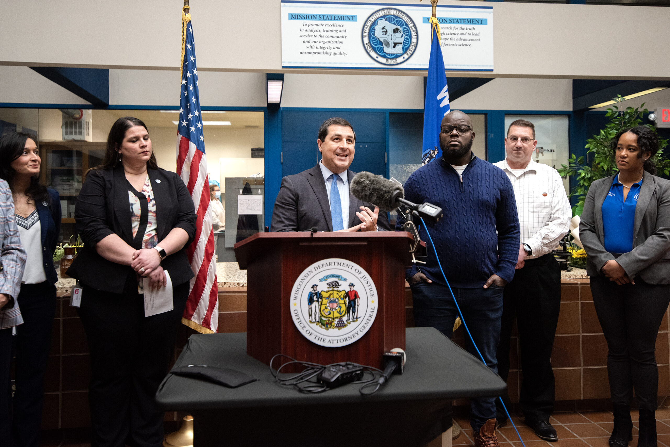 AG Josh Kaul is surrounded by other officials inside of the crime lab during a press conference.