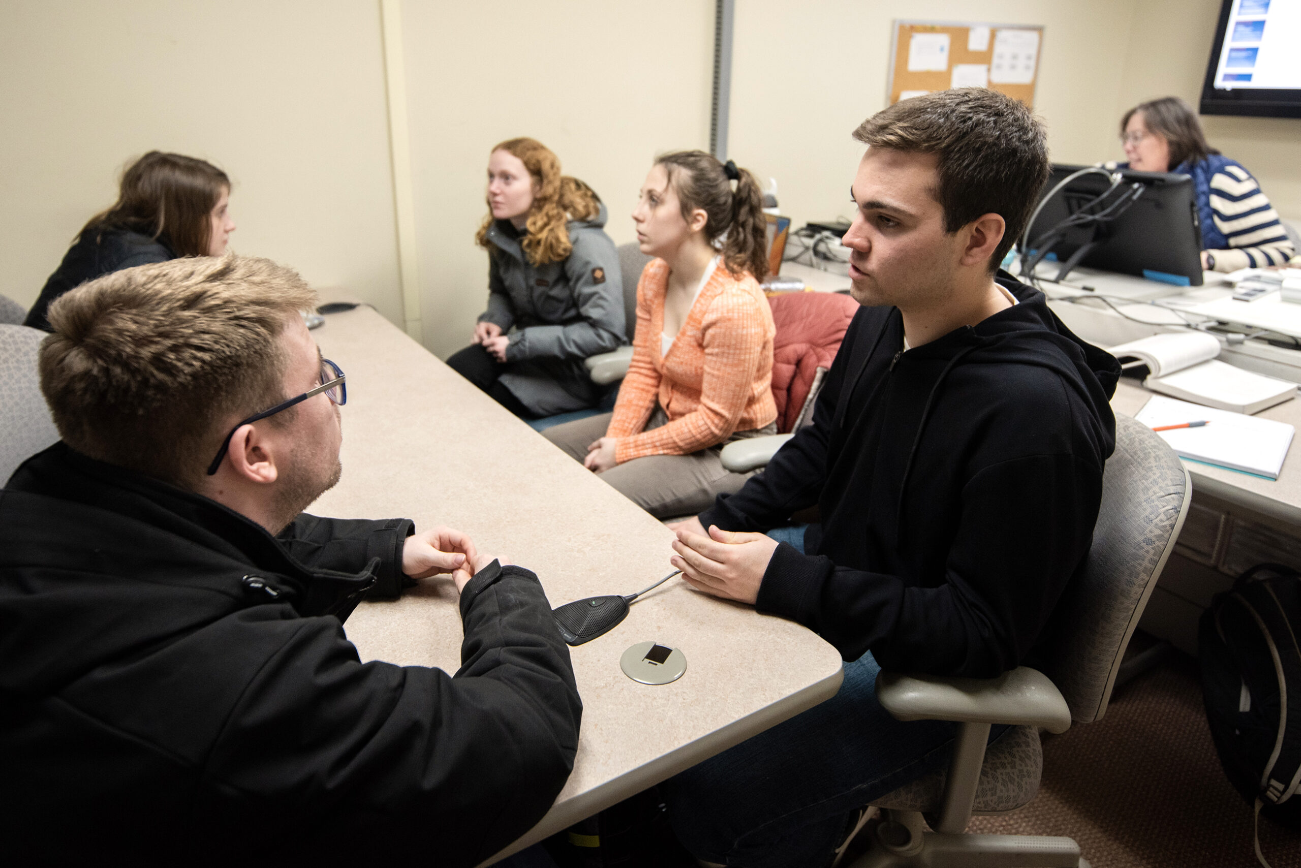 Students sit at a table in a small classroom.