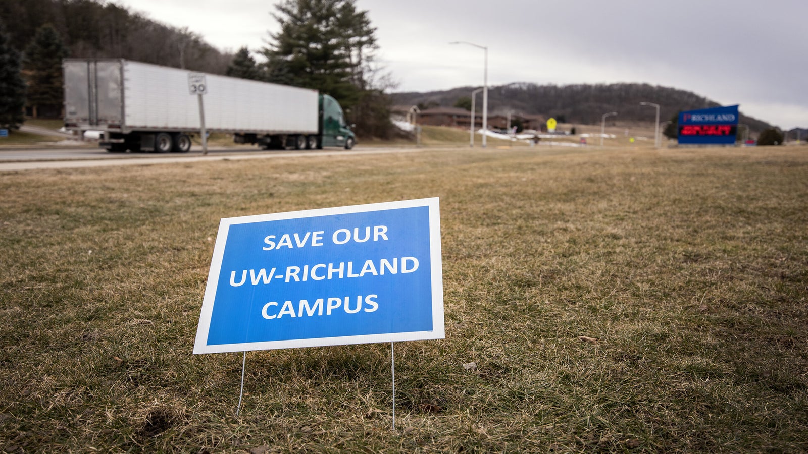 A blue yard sign says "Save our UW-Richland Campus."