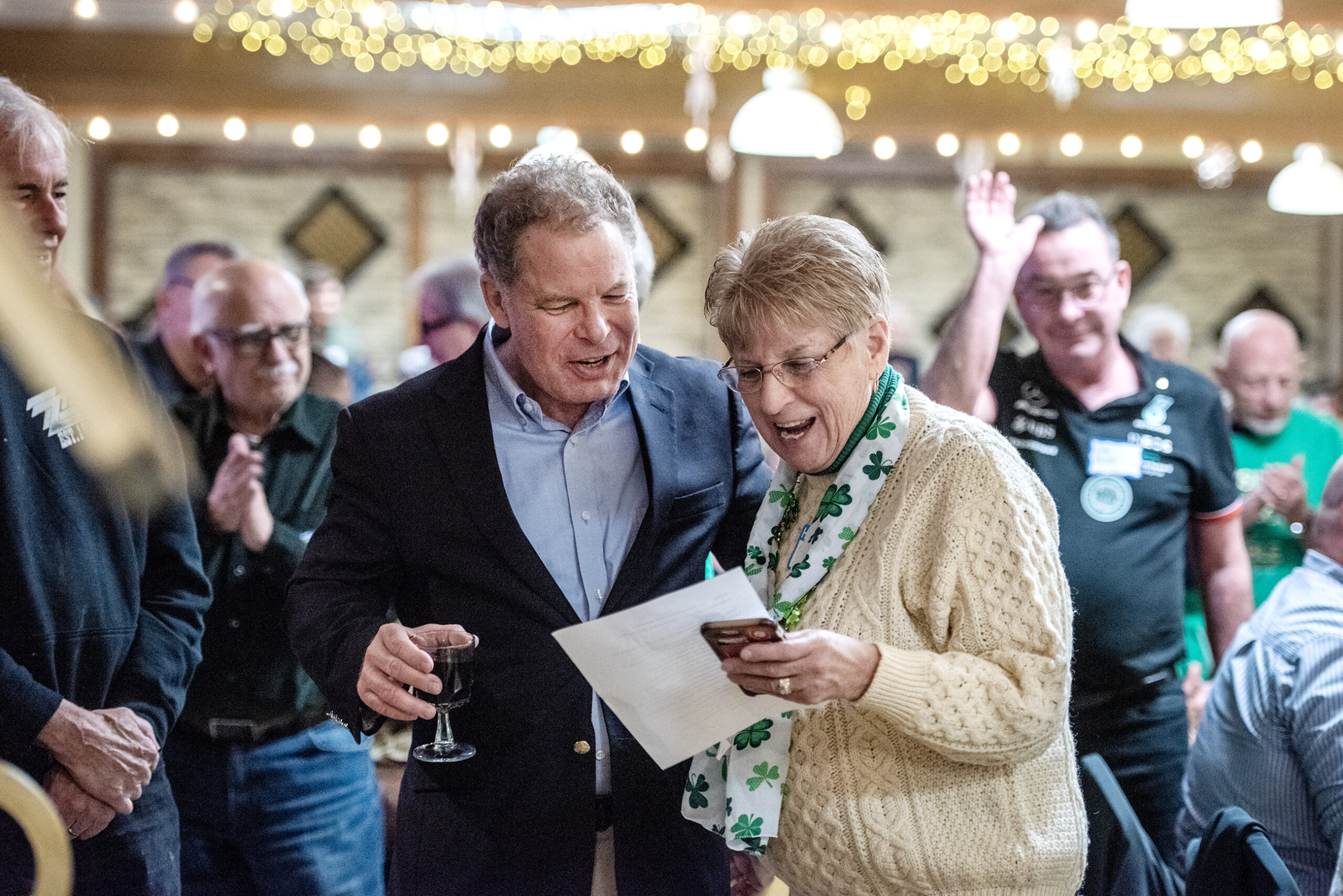 Dan Kelly holds a drink in a crowded supper club while speaking to a woman.