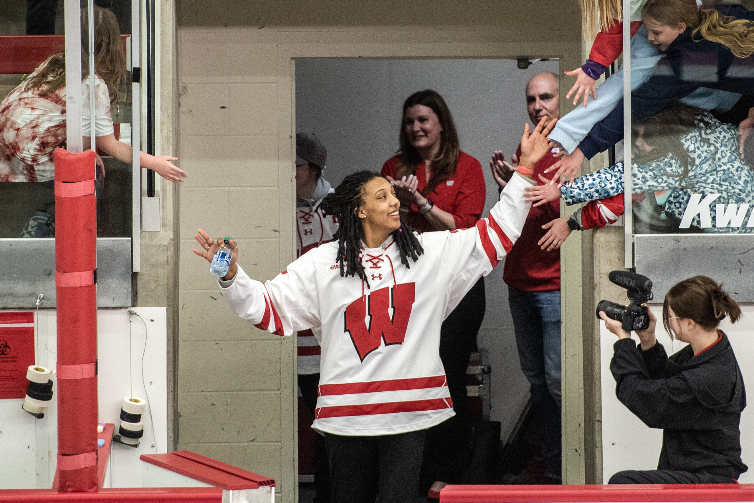 A player in a Badgers jersey smiles as she high fives fans.