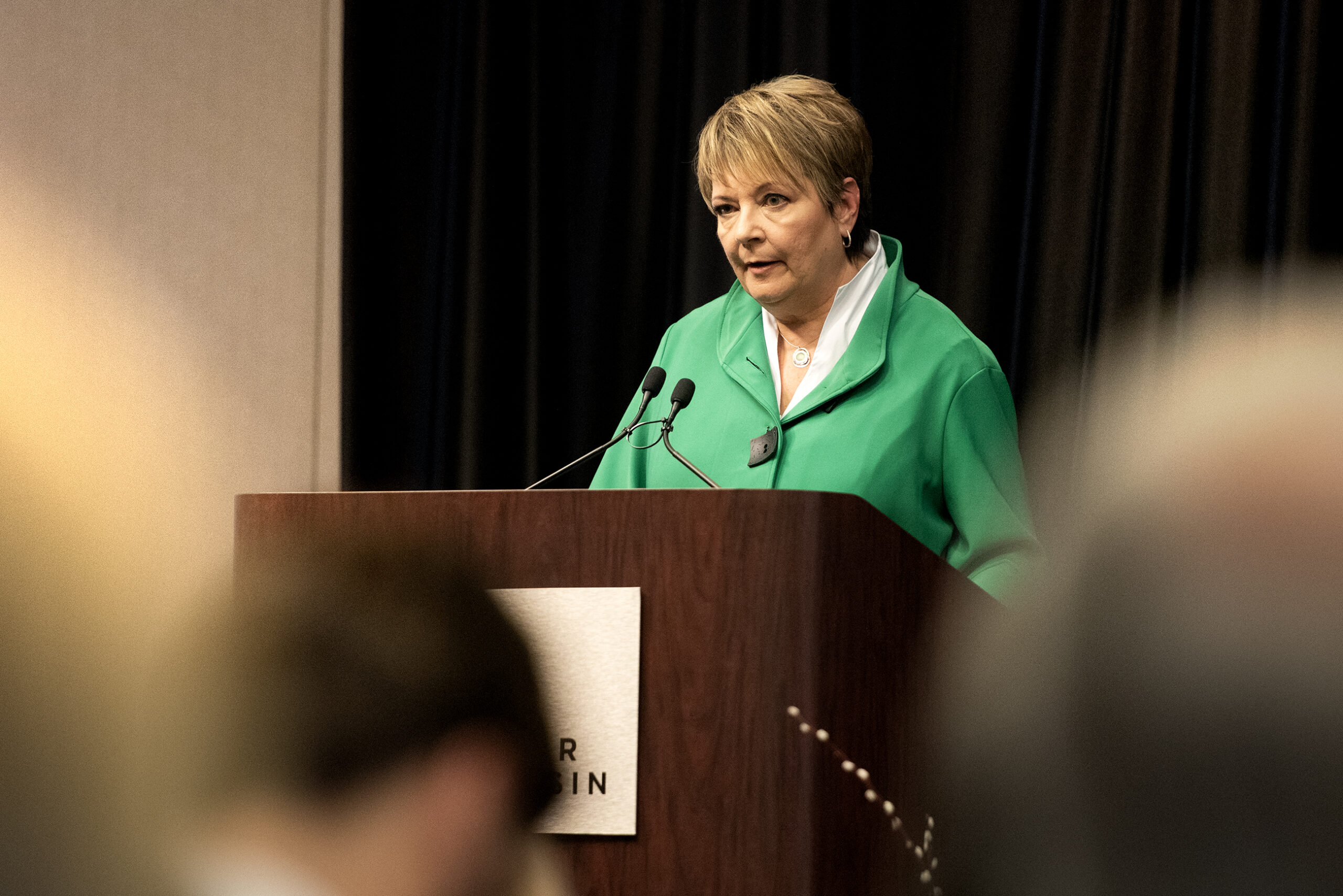 Janet Protasiewicz stands behind a podium on stage during a debate.