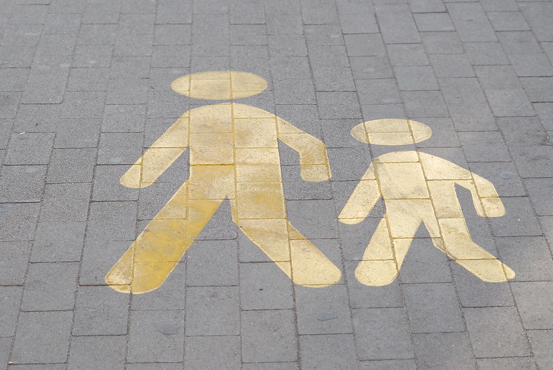 A sign depicting an adult and child crossing the street