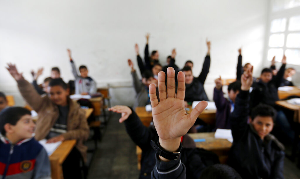 Palestinian students raise their hands while attending a class at a U.N.-run school in Gaza City, Sunday, Feb. 16, 2014. Gaza’s Hamas authorities have blocked a U.N. refugee agency from introducing a book promoting human rights into local schools, saying