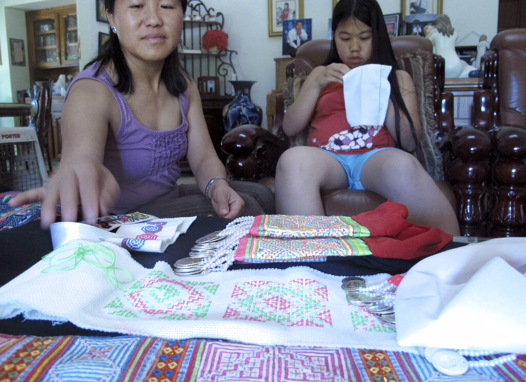 Vicky Xiong, left, teaches her daughter Rachel Lor how to do Hmong embroidery at their home in Fresno, Calif.