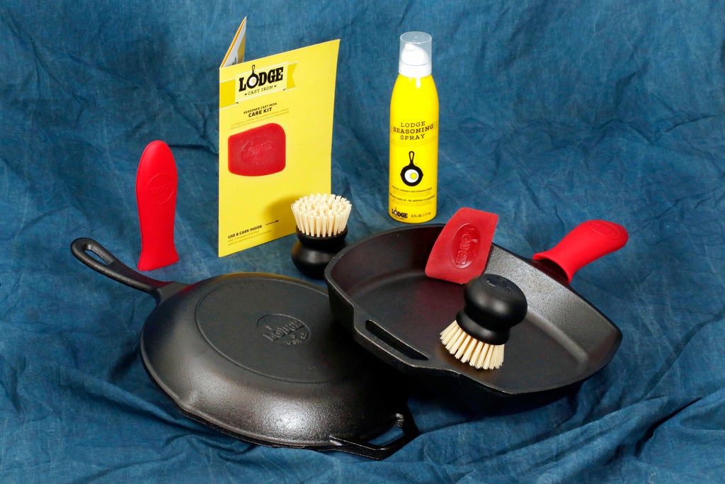 A Lodge Seasoned Cast Iron Care Kit, and two Lodge cast iron skillets are photographed in New York, Thursday, Oct. 2, 2017. Inside the kit are use and care tips, a pan scraper, scrub brush, seasoning spray, and a silicone hot handle holder as a bonus.