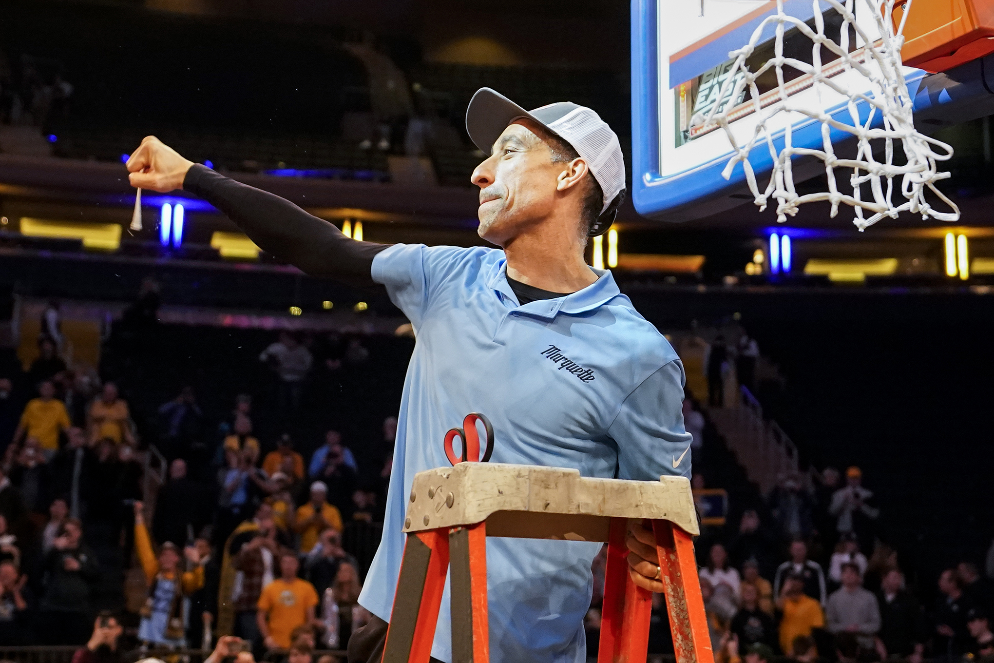 Marquette head coach Shaka Smart holds a piece of the net.