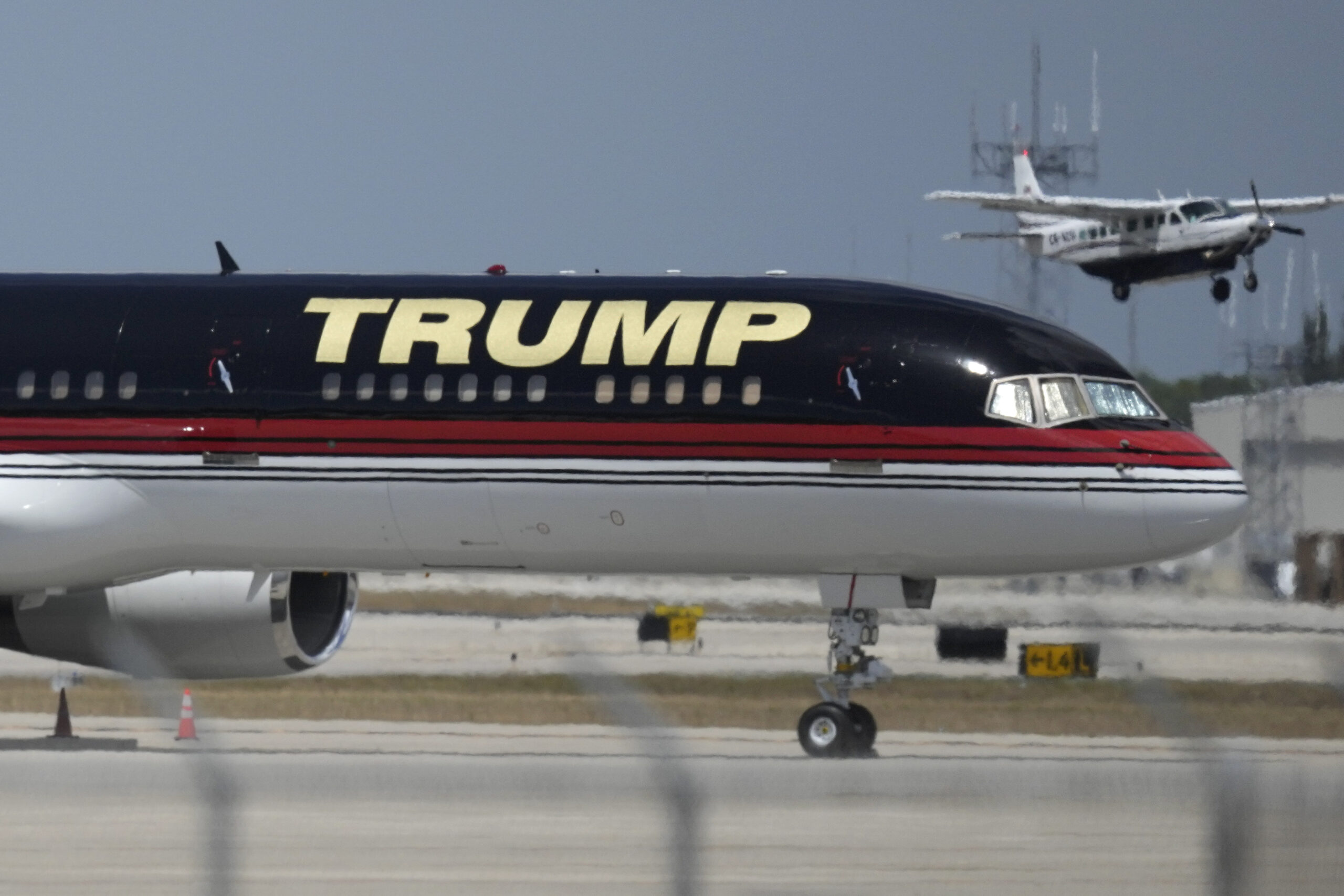 A small plane takes off past the private plane of former President Donald Trump