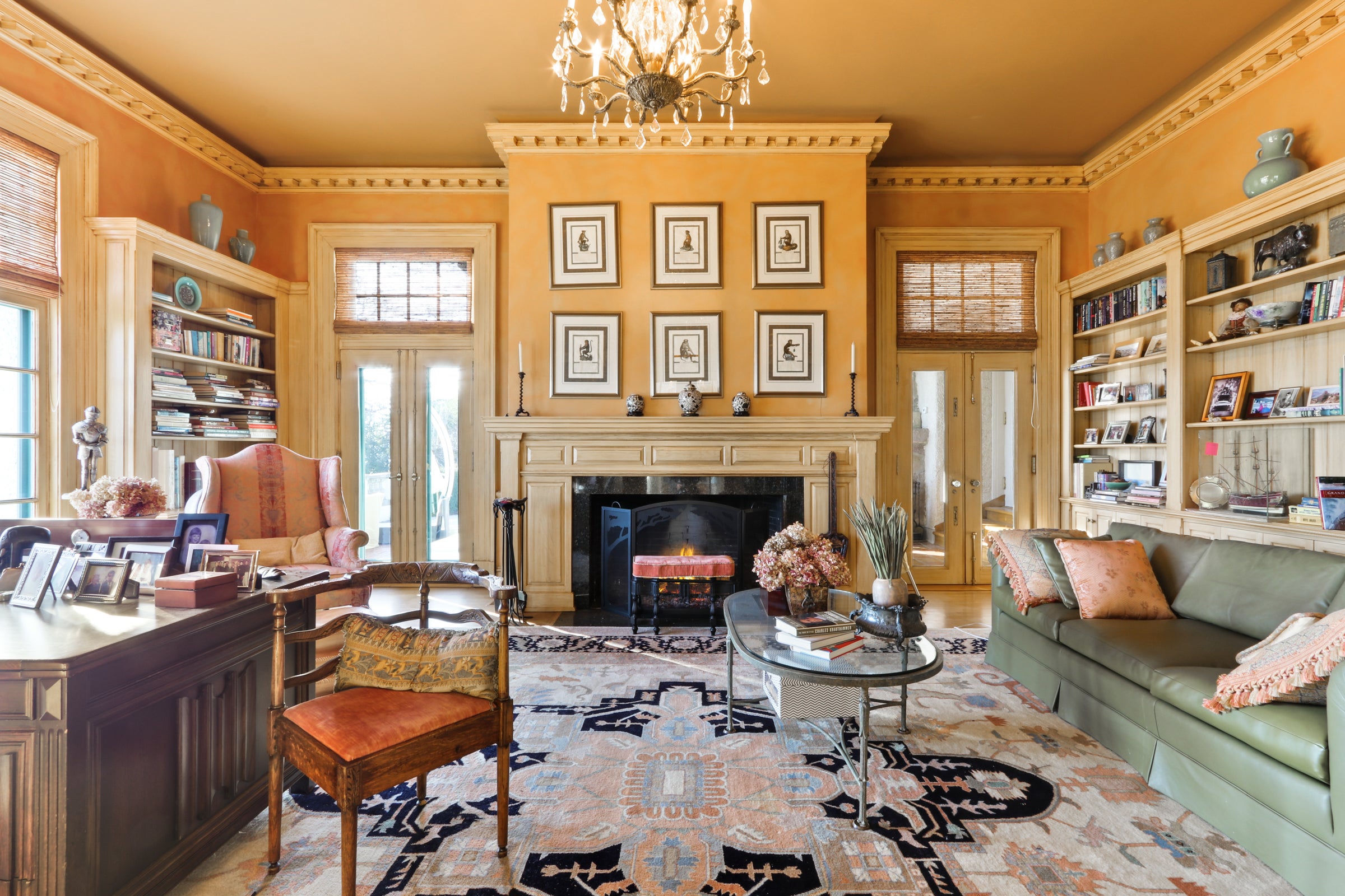 An office room in the Villa Hortensia mansion, with gold-yellow walls, a green couch, a wooden desk and several photos and shelves on the walls