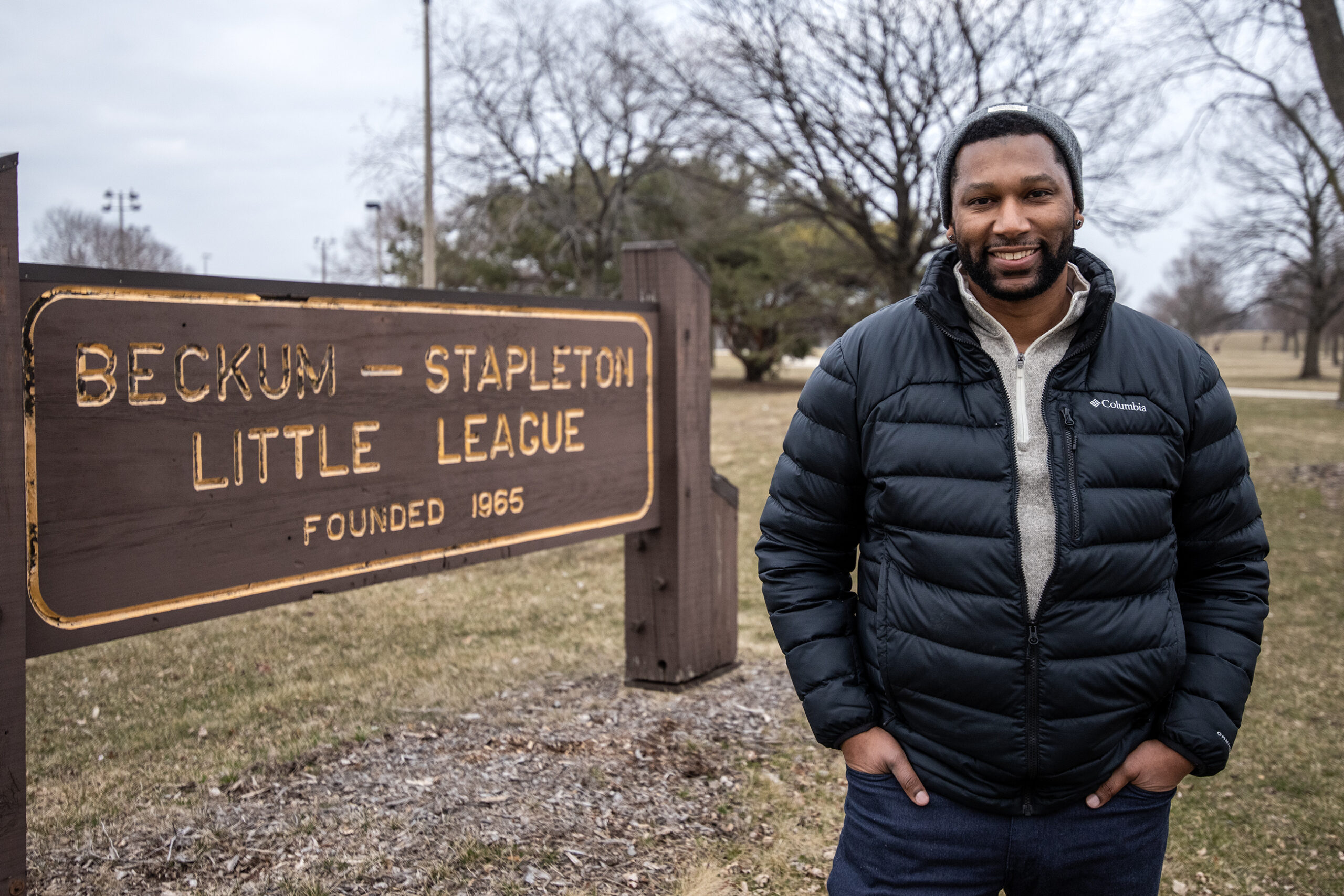 A man stands outside by a sign that says 