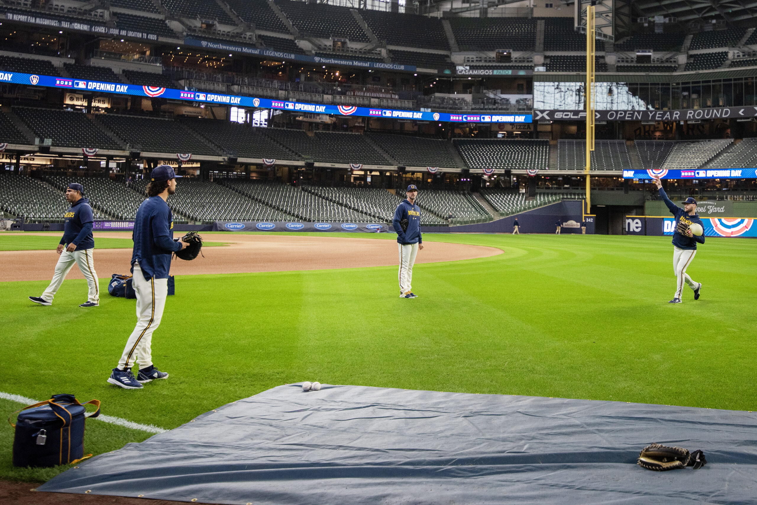 Four players stand on green grass while seats remain empty before the game.