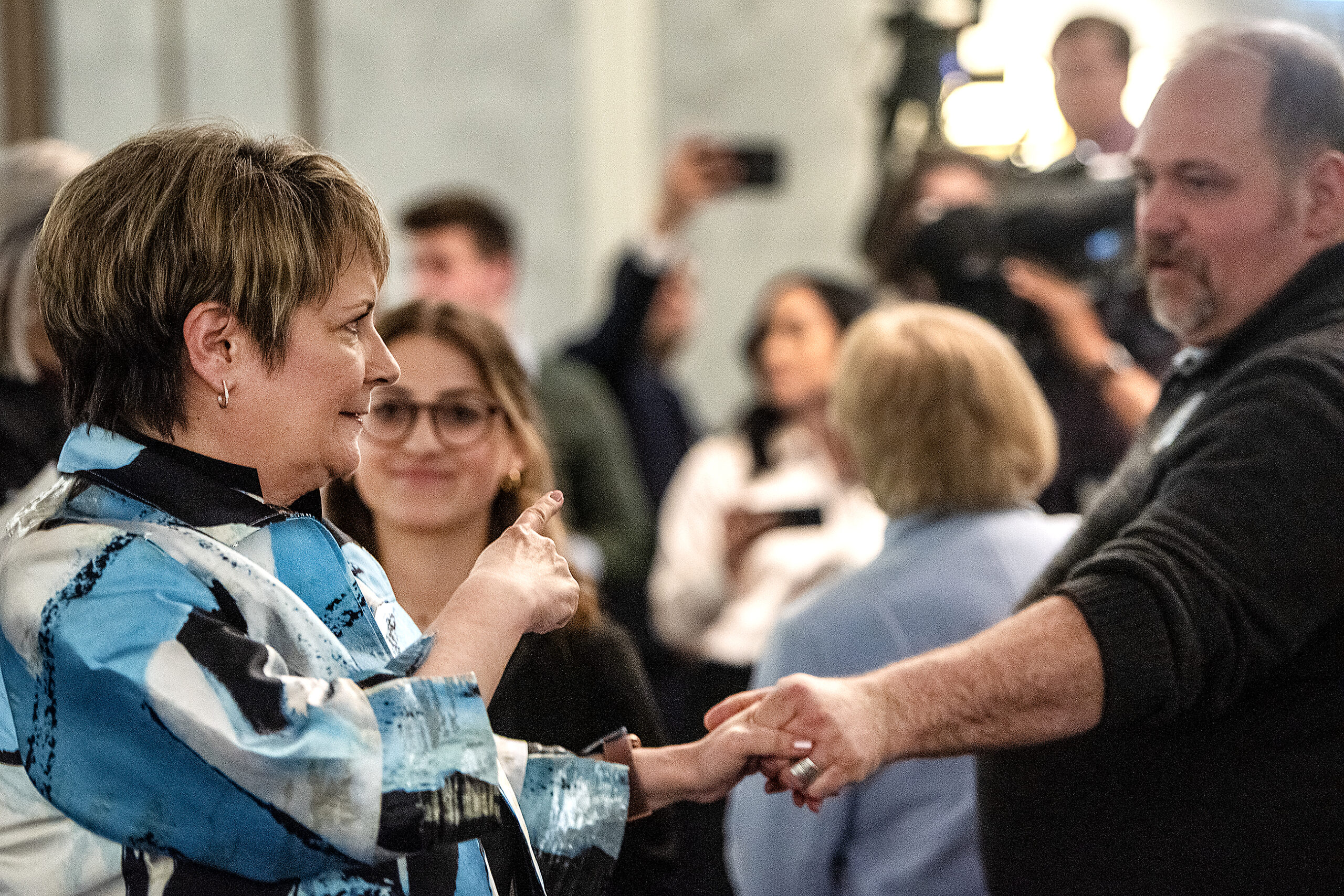 Janet Protasiewicz holds an attendees hand and points back at him.