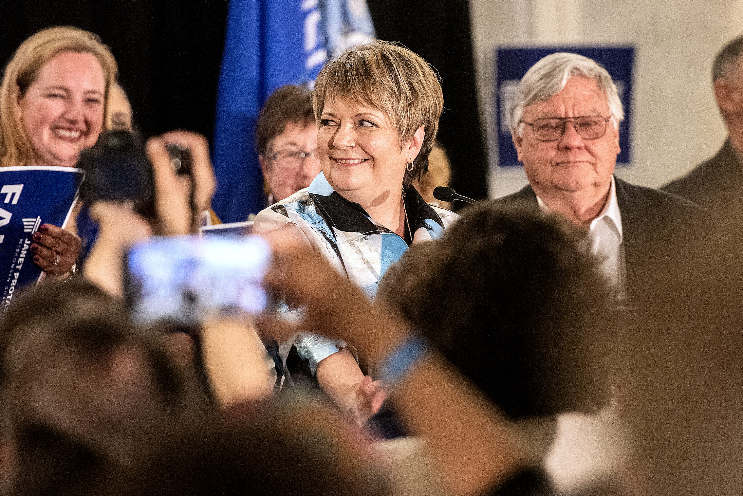 Janet Protasiewicz smiles at the crowd from behind a podium.